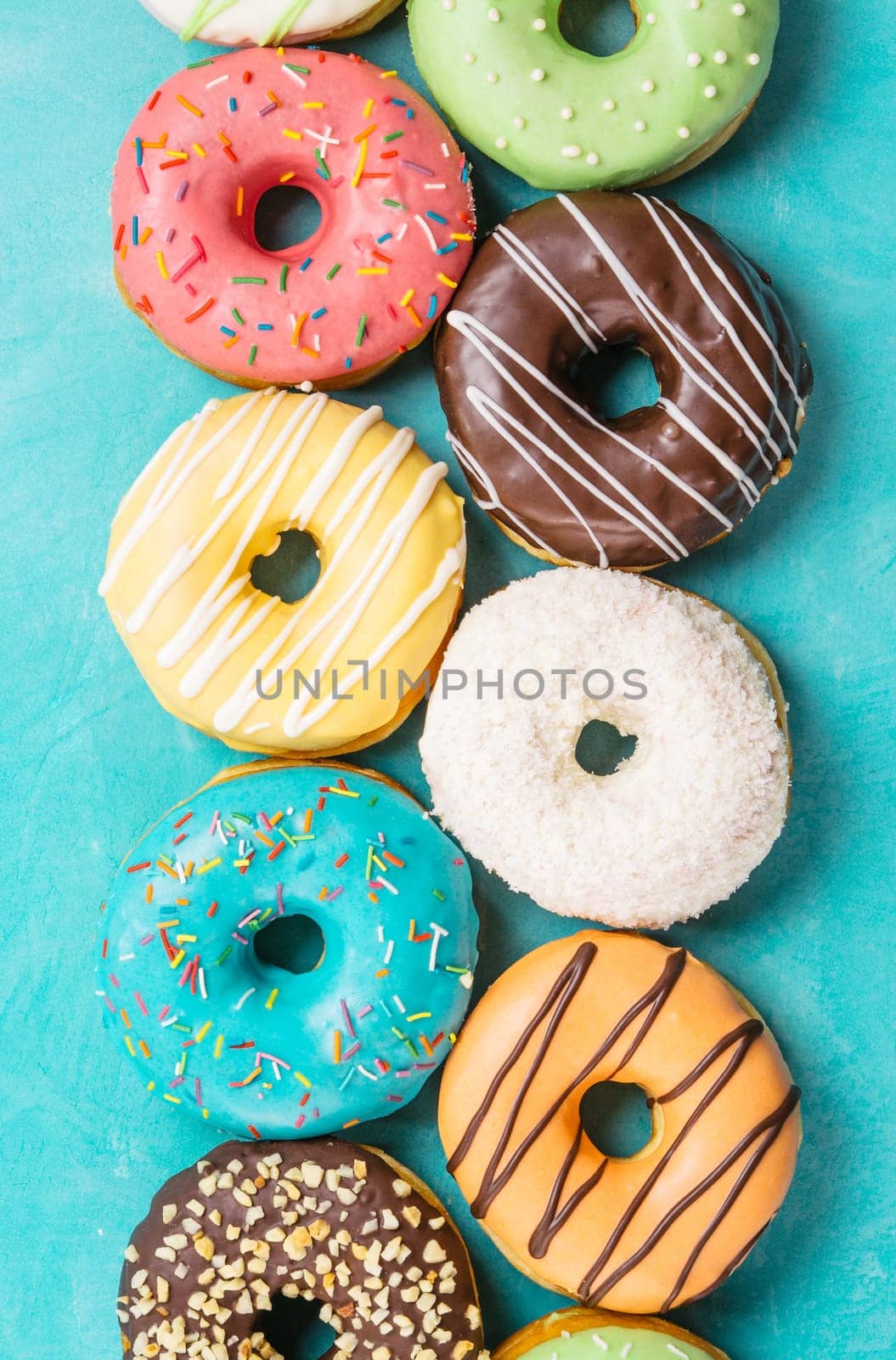 Top view of assorted donuts on blue concrete background. Colorful donuts background. Various glazed doughnuts with sprinkles.