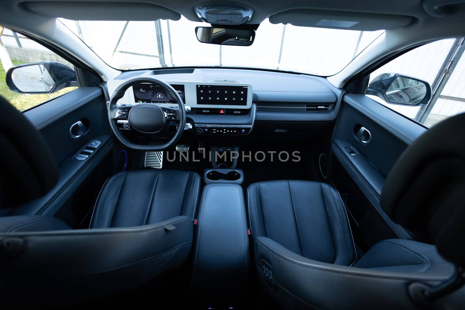 Electric car interior details adjustments. Inside car interior with front seats, driver and passenger, textile, windows, console, gear shift, electric buttons, digital speedometer, steering wheel