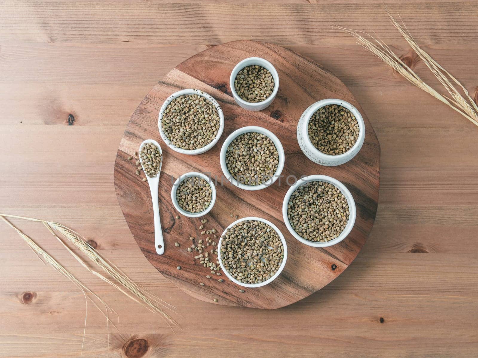 Hemp seeds in small white bowls and spoon on wooden table. Set of small bowls with raw organic unrefined hemp seed. Superfood and vegan concept. Top view or flat lay.Copy space for text