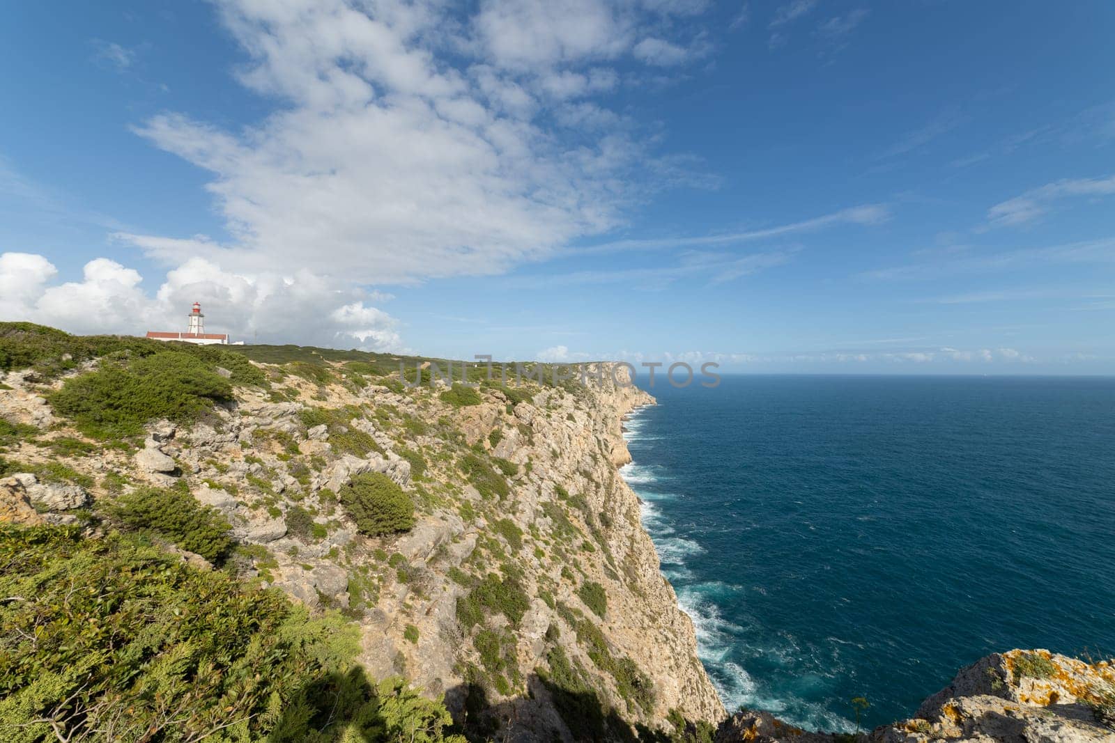 A beautiful view of the ocean with a lighthouse in the distance by Studia72