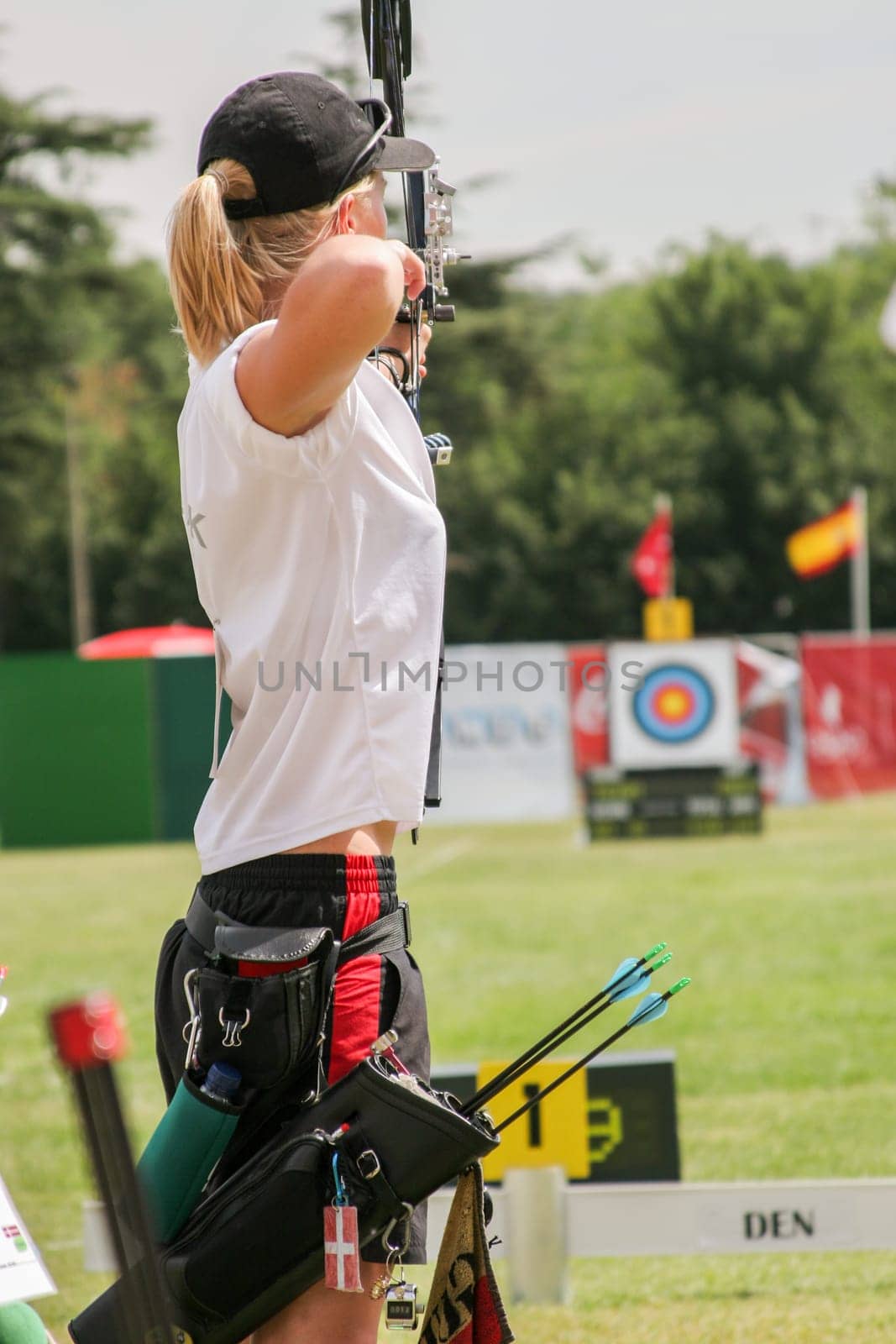 Female archer in the shooting position, facing a line of targets in competition.