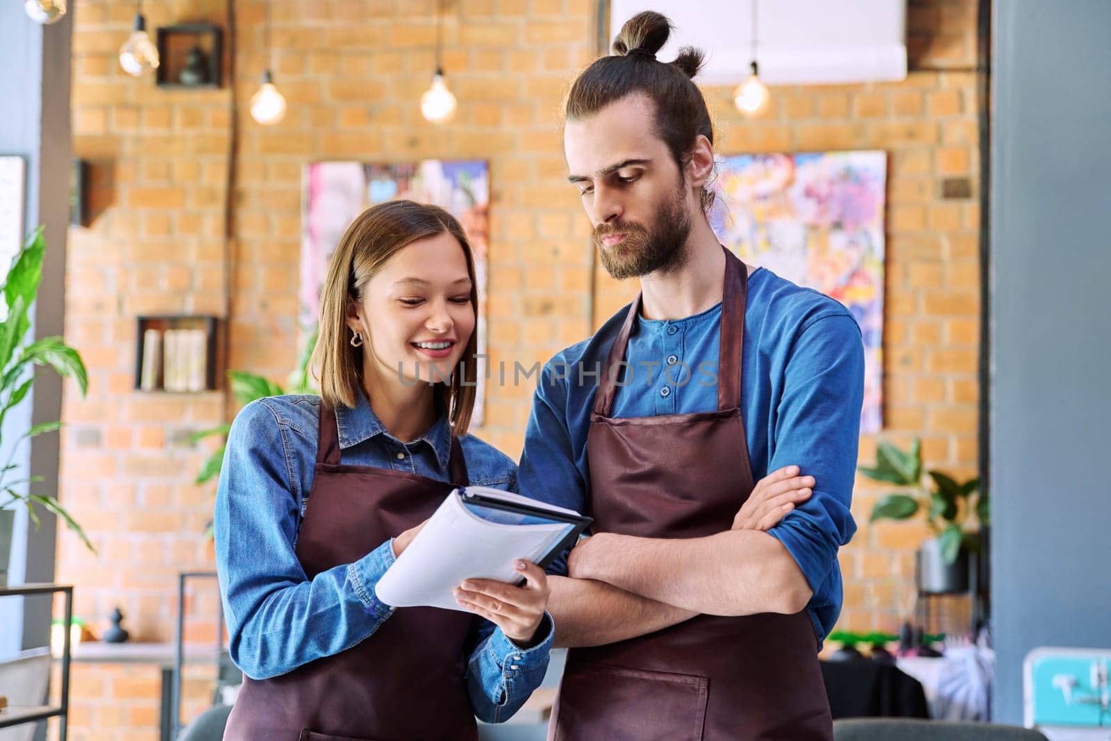 Business team, confident colleagues young man and woman in aprons with notebook by VH-studio