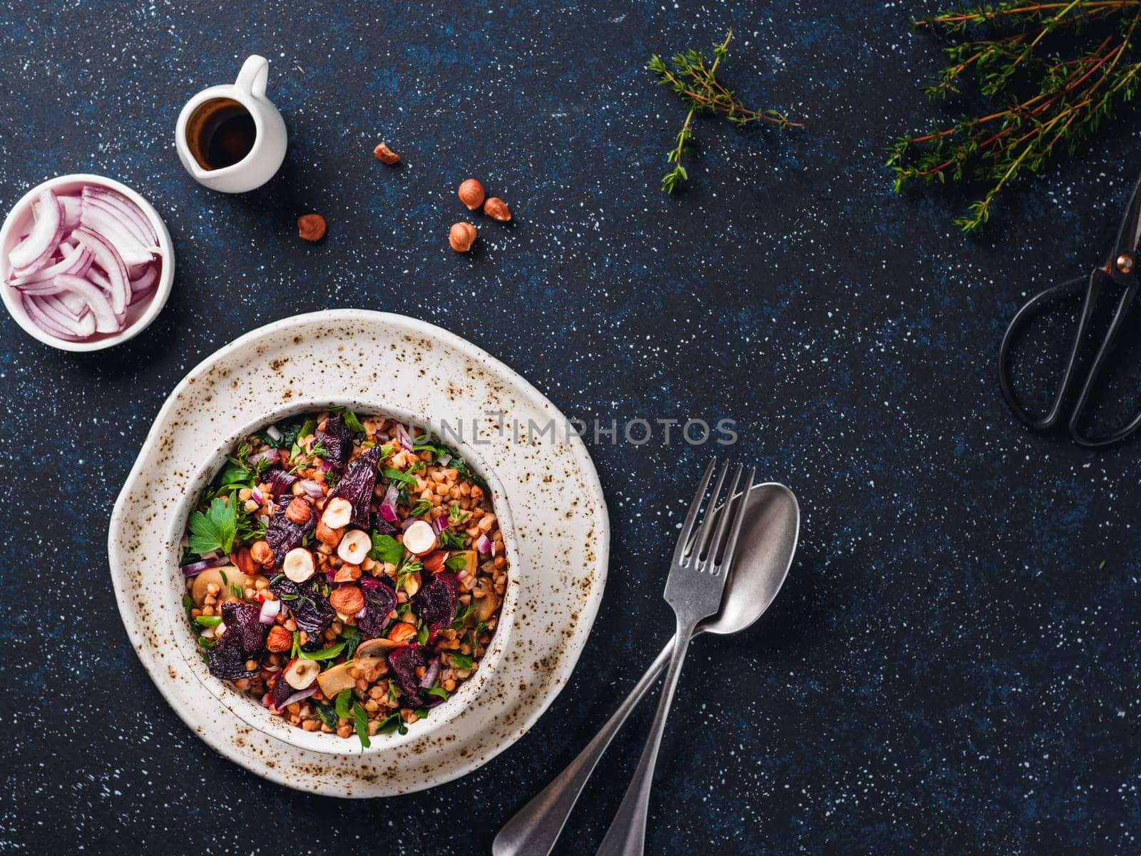 Warm buckwheat and beetroot salad on dark background. Vegetarian diet idea and recipe -salad with beetroot, buckwheat, mushrooms, onion, fresh herbs,hazelnut. Top view or flat-lay. Copy space for text