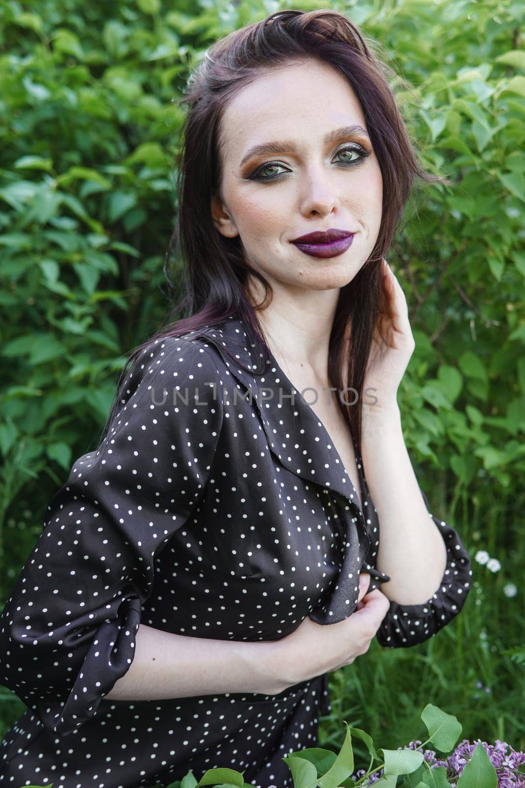 A fashionable girl with dark hair, a spring portrait in lilac tones in summer. Bright professional makeup