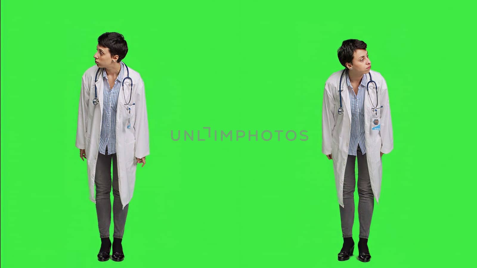 Woman physician looking around for patients to come at checkup exams, waiting for someone standing against greenscreen backdrop. General practitioner with white coat feeling impatient. Camera A.