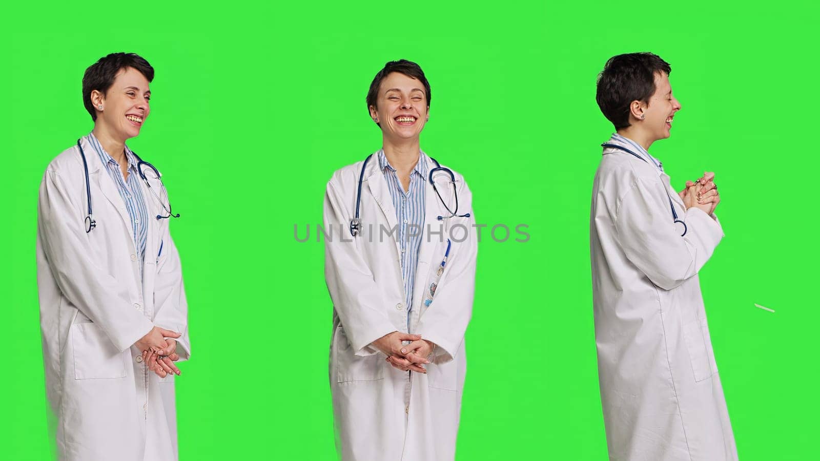 Portrait of general practitioner laughing at something against greenscreen backdrop, feeling joyful and confident with her healthcare expertise. Woman medic in white coat smiling in studio. Camera B.