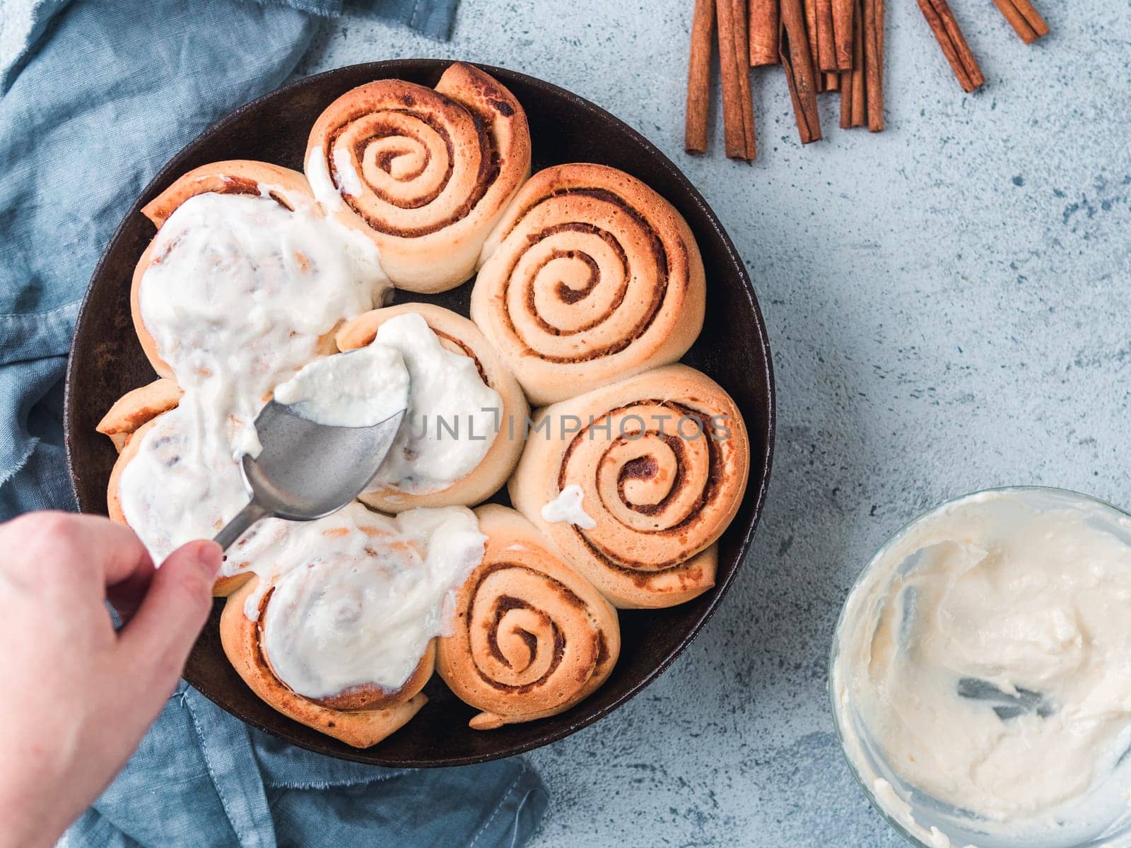 Hand Spreading Frosting on Cinnamon Rolls, copy space by fascinadora