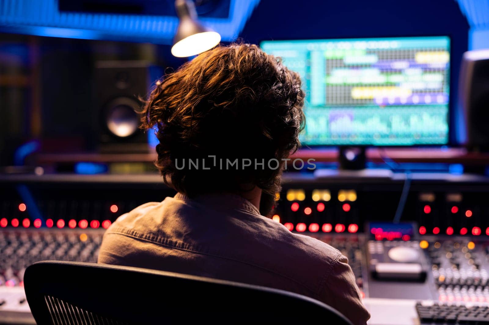 Sound designer tuning audio recordings with faders and buttons on control desk in professional music studio, mixing and mastering tracks for a new album. Adjusting volume levels with equalizer.