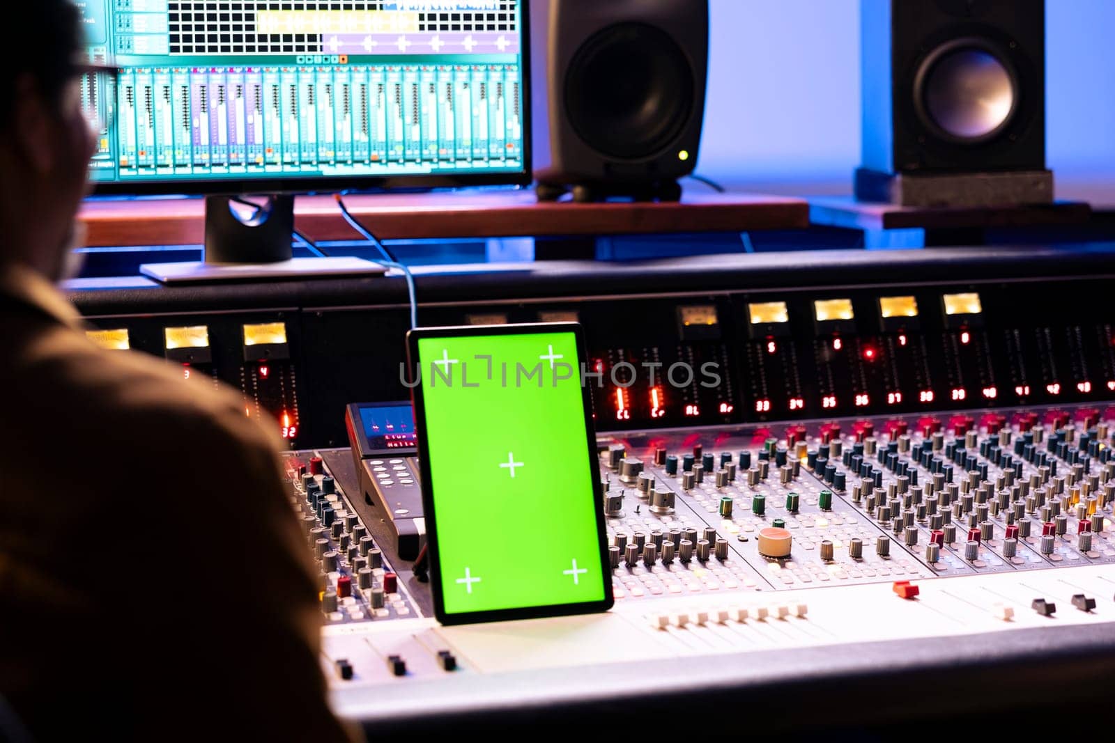 Singer and audio engineer collaborating on new hit song in studio, looks at mockup on gadget next to soundboard control desk panel board. Technician and artist recording new music, mixing console.