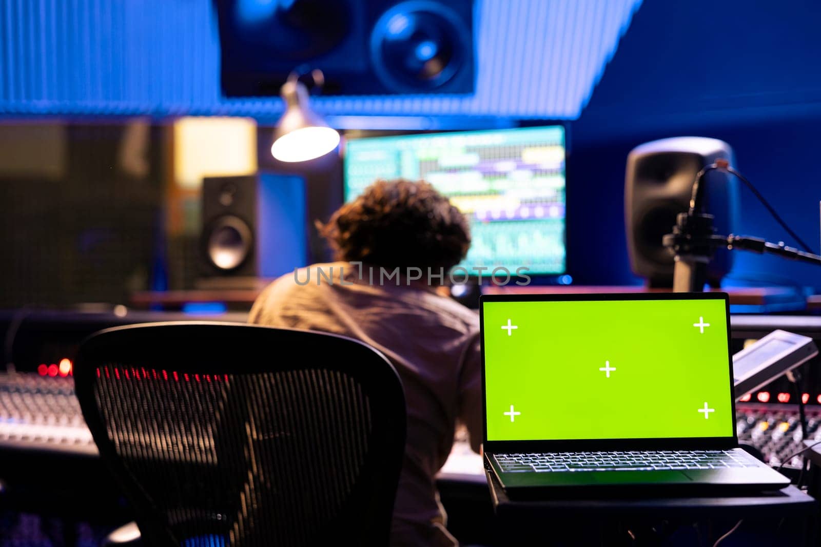 Musician and sound engineer working on a new song with isolated screen, editing and adjusting volume levels on tunes recorded. Team of artists producing music and composing tracks in control room.