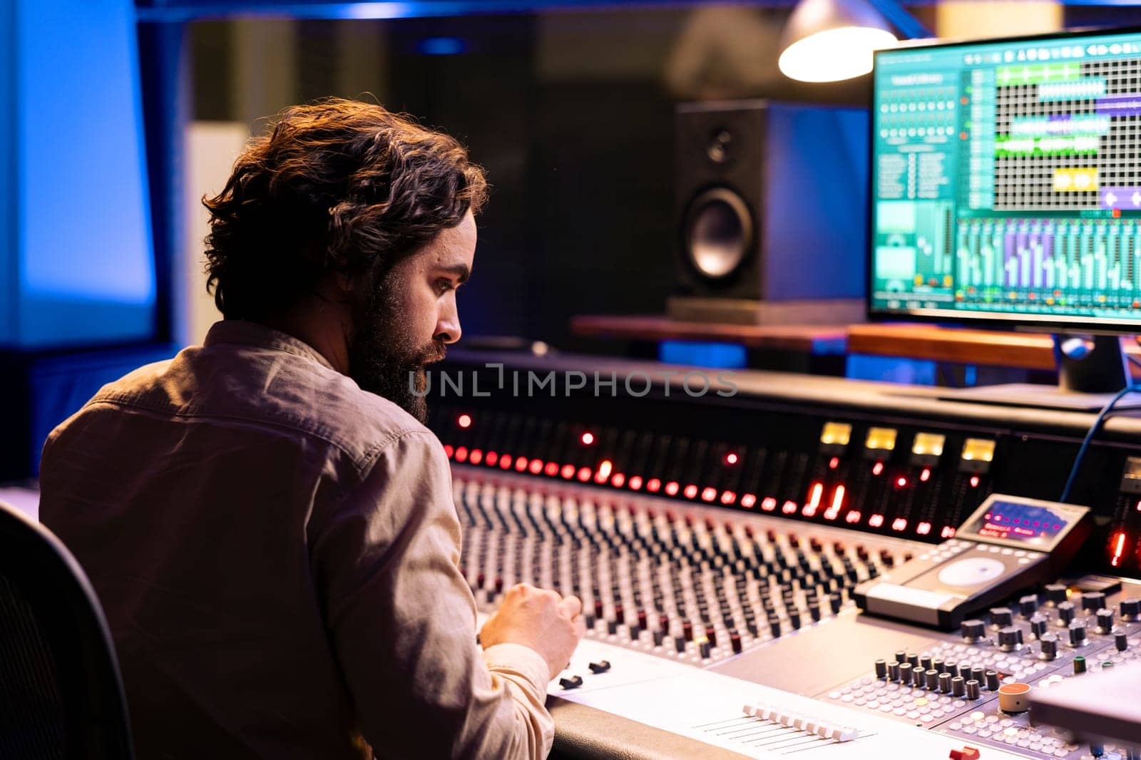 Music producer working on mixing and mastering music with daw software, editing tracks with audio console dashboard. Young sound designer creating sounds and tunes in professional studio.