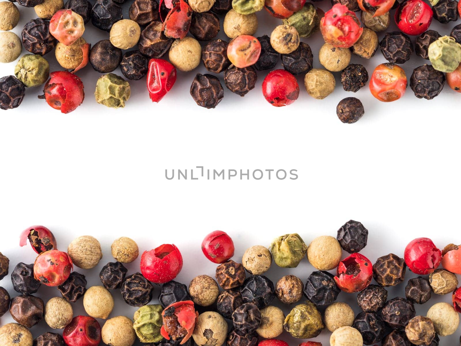 Mixed peppercorns background with white copy space in center. Food background with peppercorns. Different colored peppercorns pattern on white background, top view or flat lay