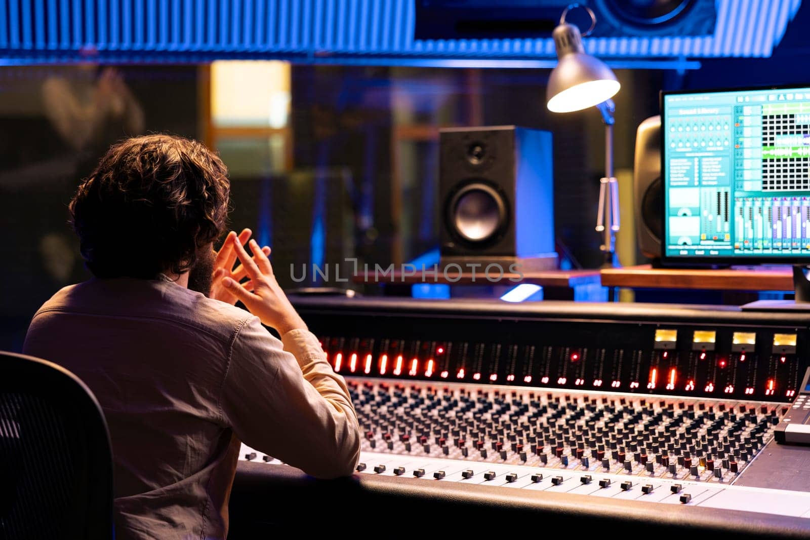 Focused sound designer processing and creating tunes in control room by DCStudio