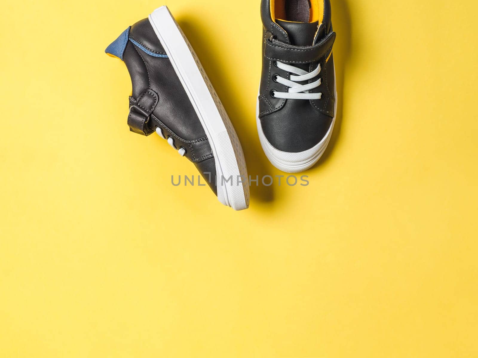 pair of new kids or adult sneakers on yellow background, top view. Flat lay gray and yellow or mustard color sneakers shoes on colorful bright background with copy space for text or design
