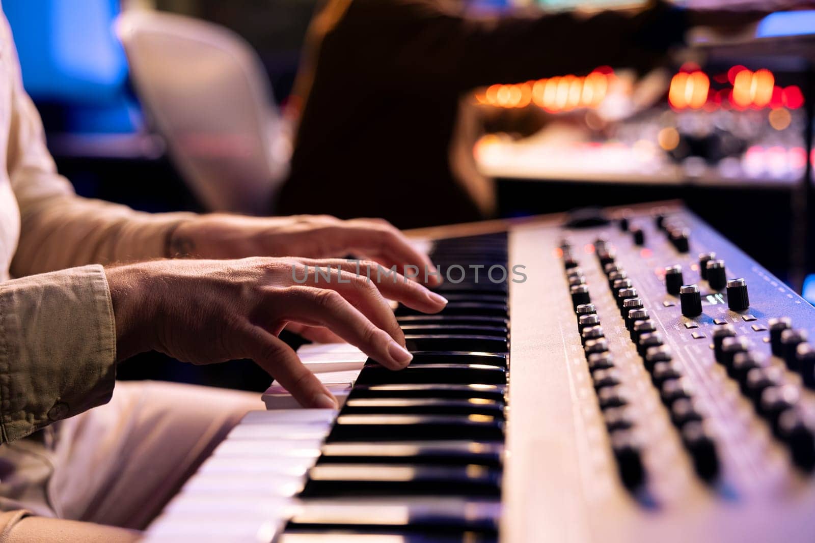 Male artist playing notes on electronic midi controller in studio by DCStudio