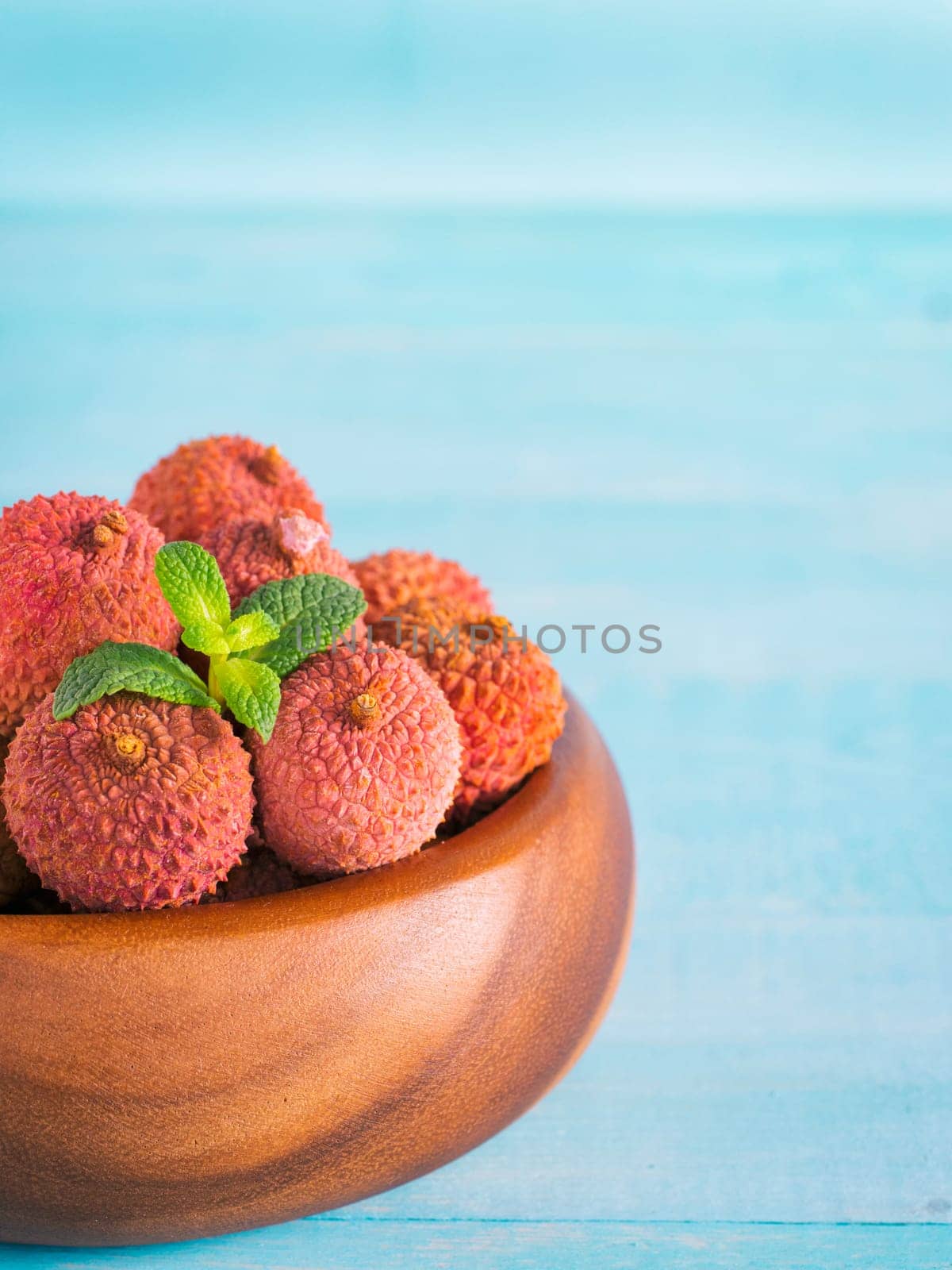 lychee fruit in clay plate on blue wooden background close up