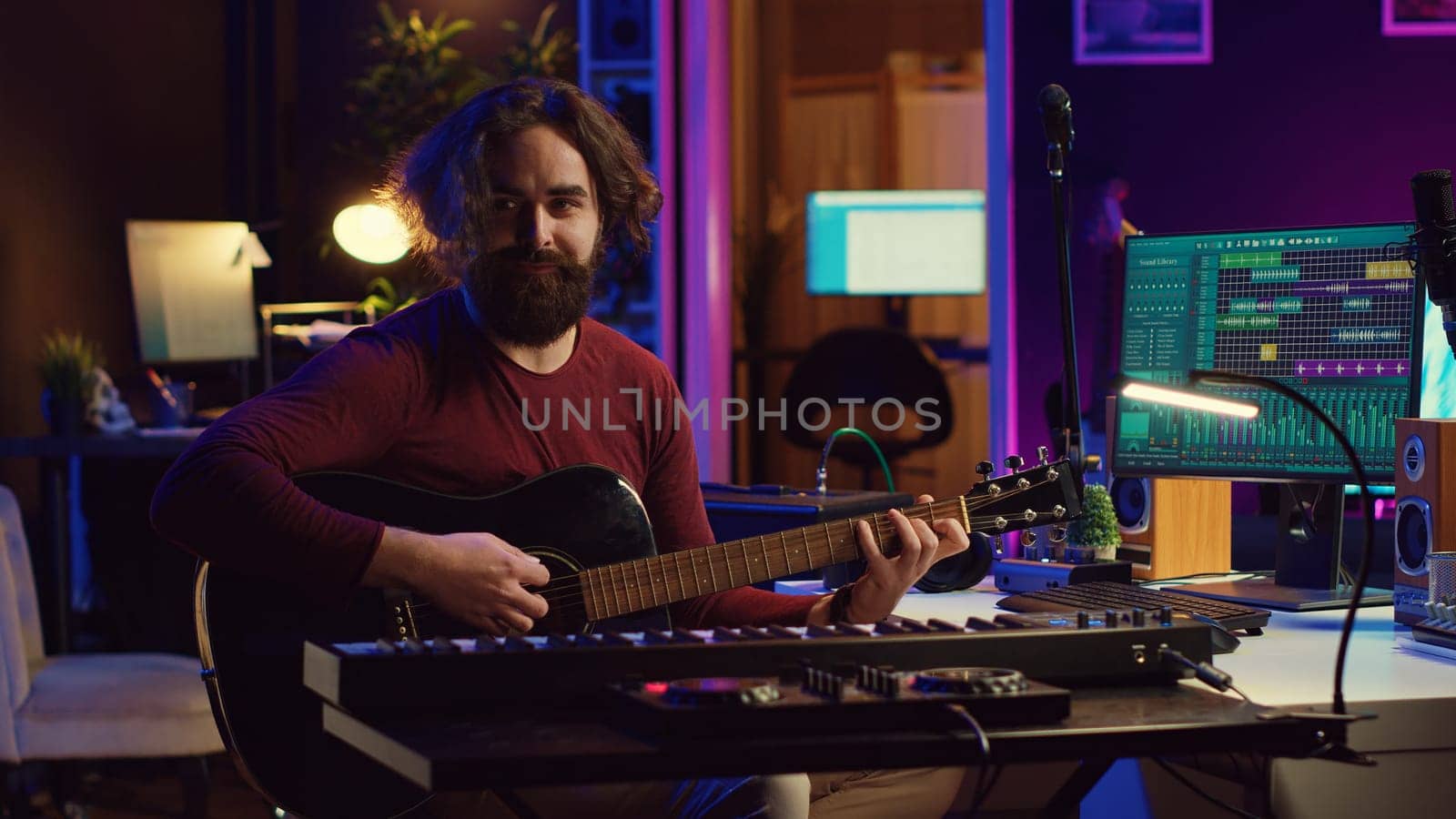 Musician plays acoustic guitar and records melody to compose new song and tunes. Computer screen showing DAW software interface with soundtracks, sound engineer in music production. Camera A.