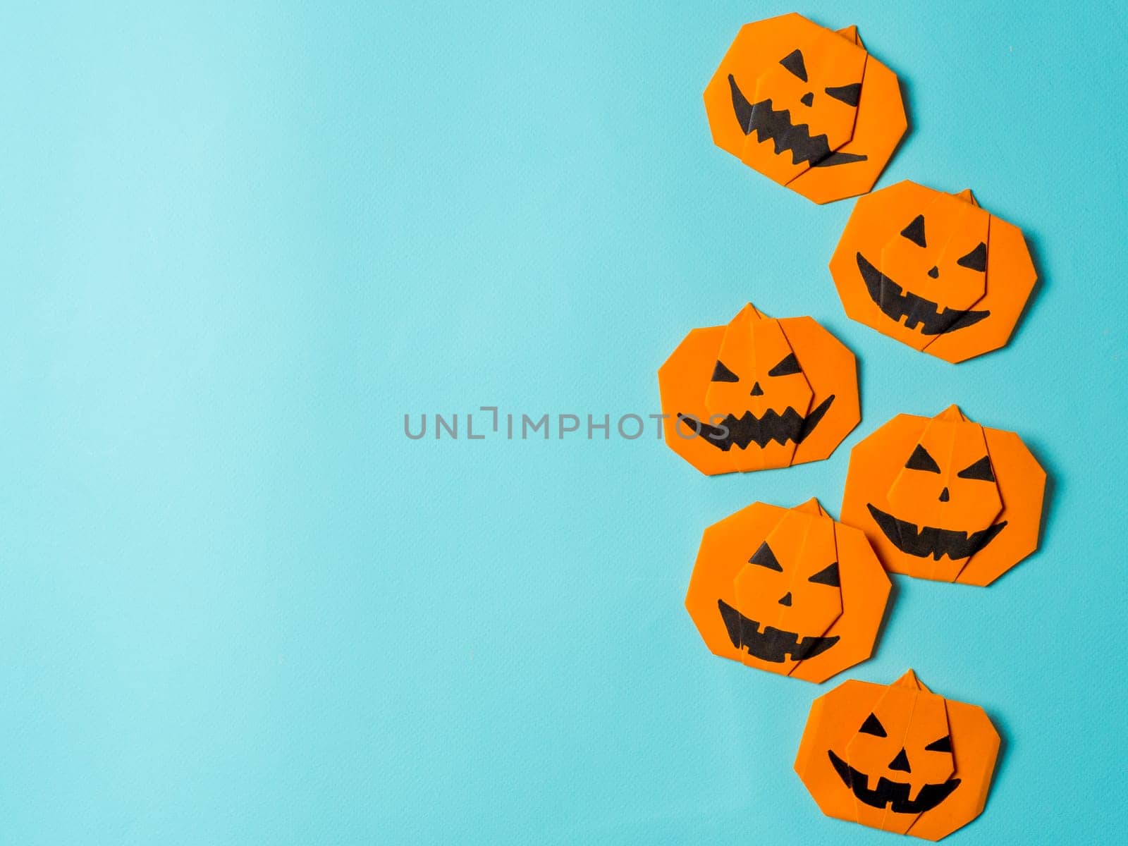 Halloween concept. Paper origami pumpkin on bright blue background. Simple idea for halloween - easy made paper pumpkins on light blue color background. Copy space for text.