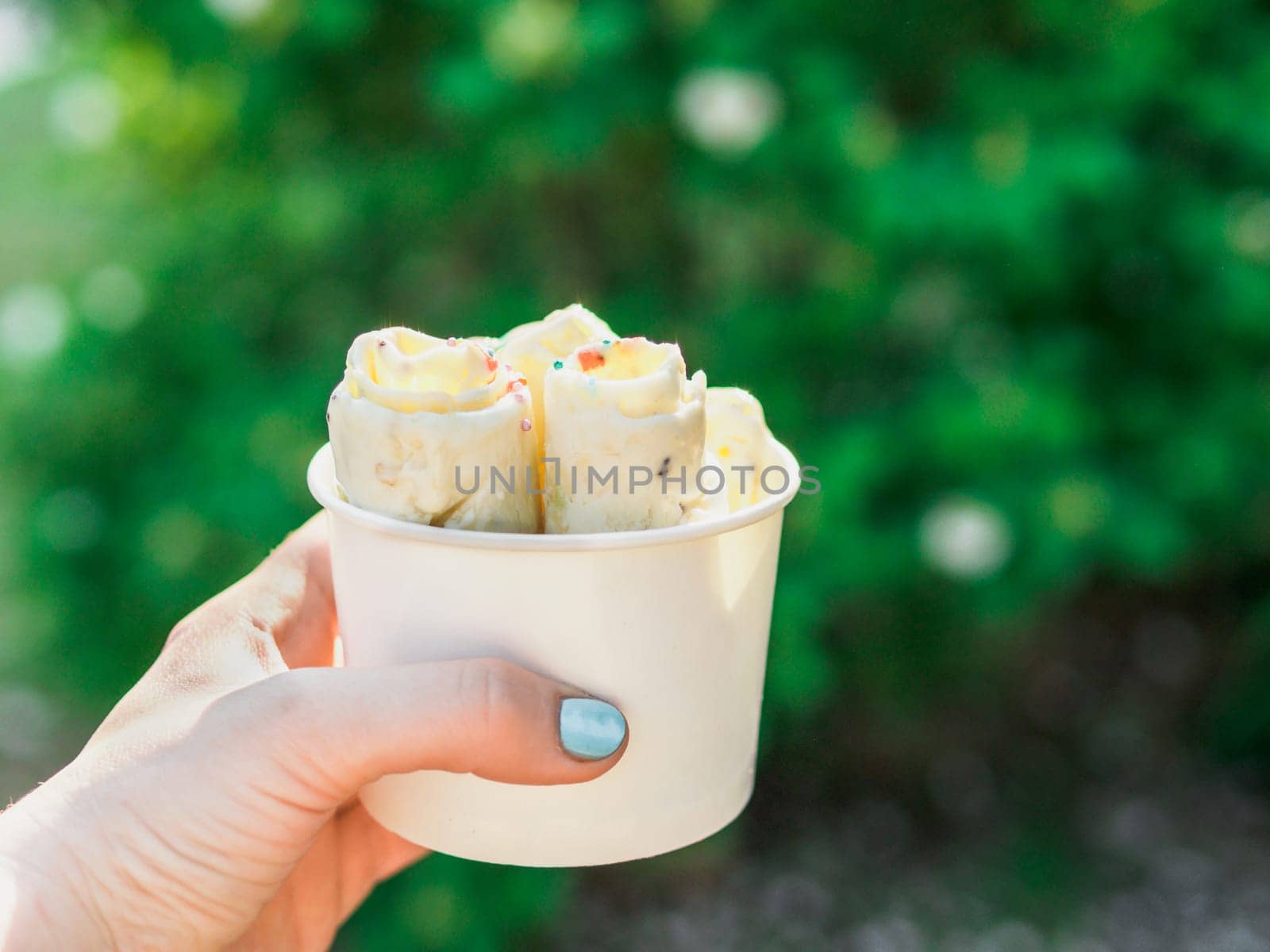 Hand holding rolled ice cream in cone cup by fascinadora