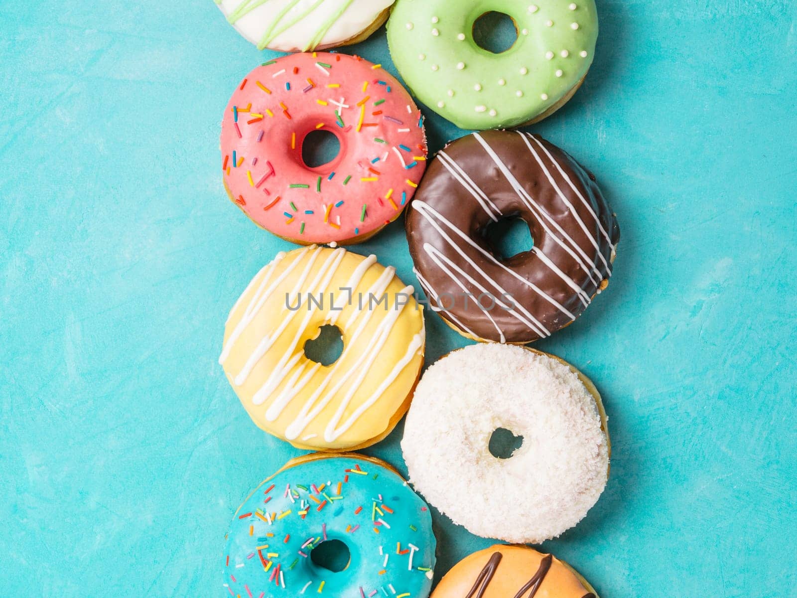 Top view of assorted donuts on blue concrete background. Colorful donuts background. Various glazed doughnuts with sprinkles.