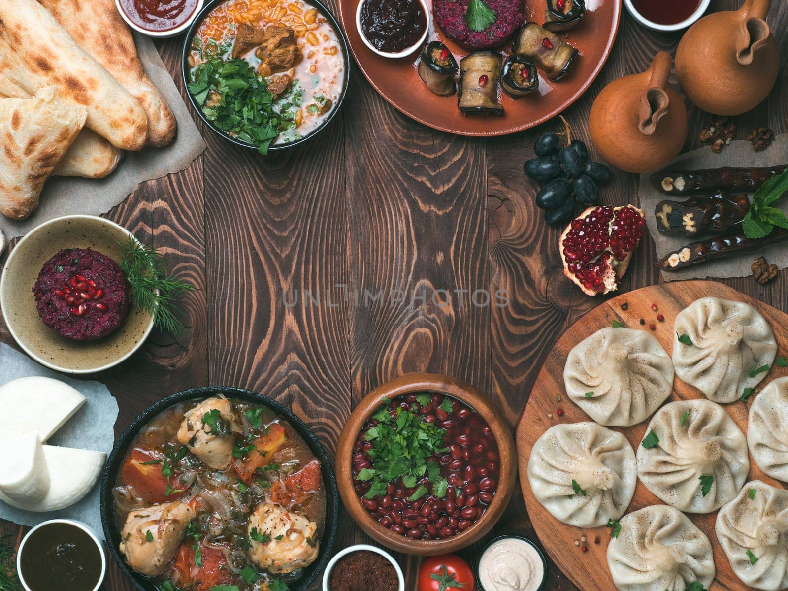 View from above of georgian cuisine on brown wooden table.Traditional georgian food-khinkali,kharcho,chahokhbili,phali,lobio and local sauces - tkemali, satsebeli, adzhika.Top view.Copy space for text