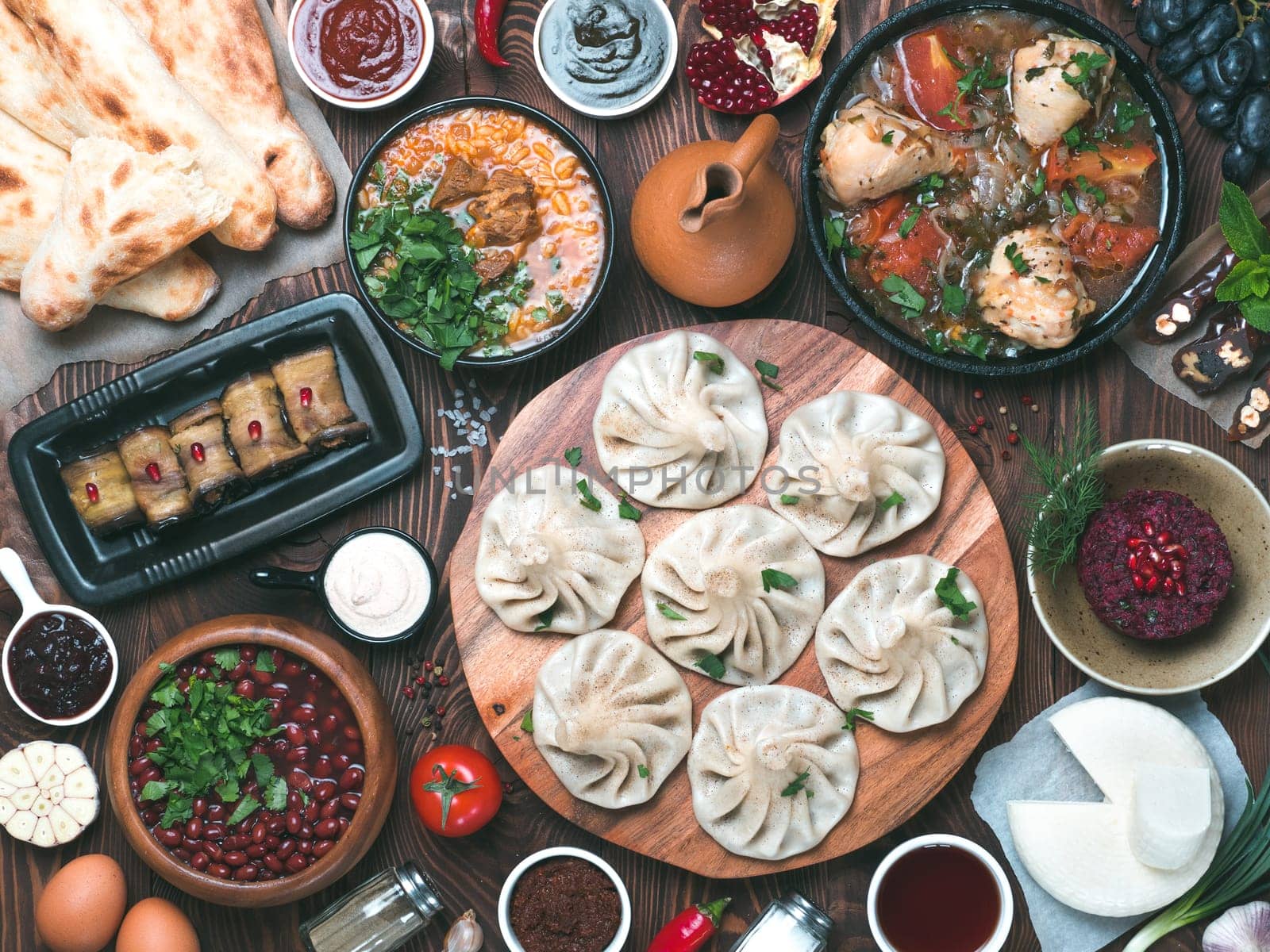 View from above of georgian cuisine on brown wooden table. Traditional georgian cuisine and food - khinkali, kharcho, chahokhbili, phali, lobio and local sauces - tkemali, satsebeli, adzhika. Top view