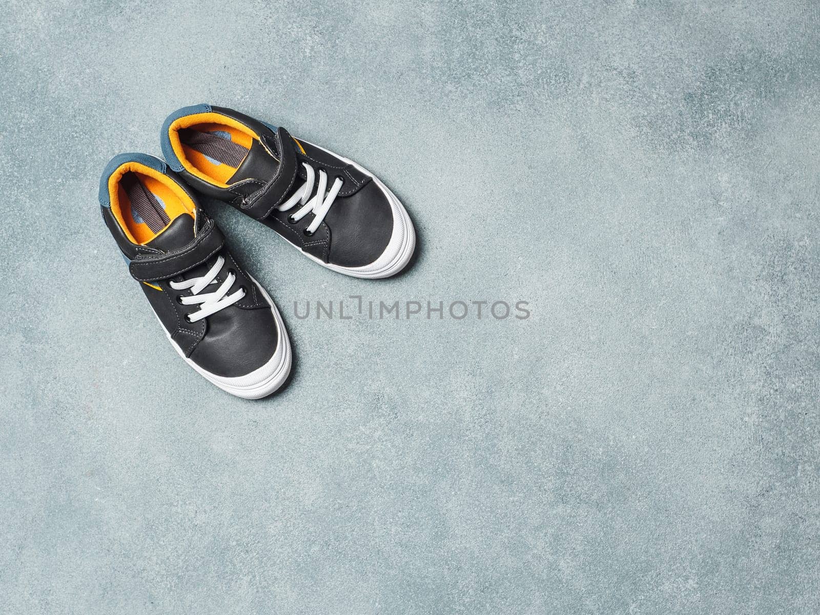 Gray and yellow sneakers on gray background by fascinadora