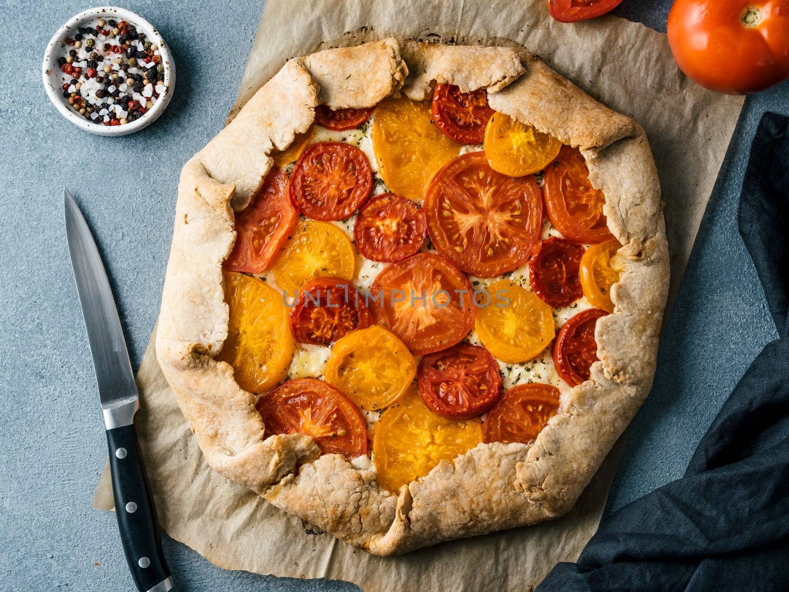 Savory fresh homemade tomato tart or galette.Ideas and recipes for healthy lunch,appetiezer- whole wheat or rye-wheat pie with tomatoes,parmesan cheese,mozzarella.Harvest tomatoes.Top view or flat lay