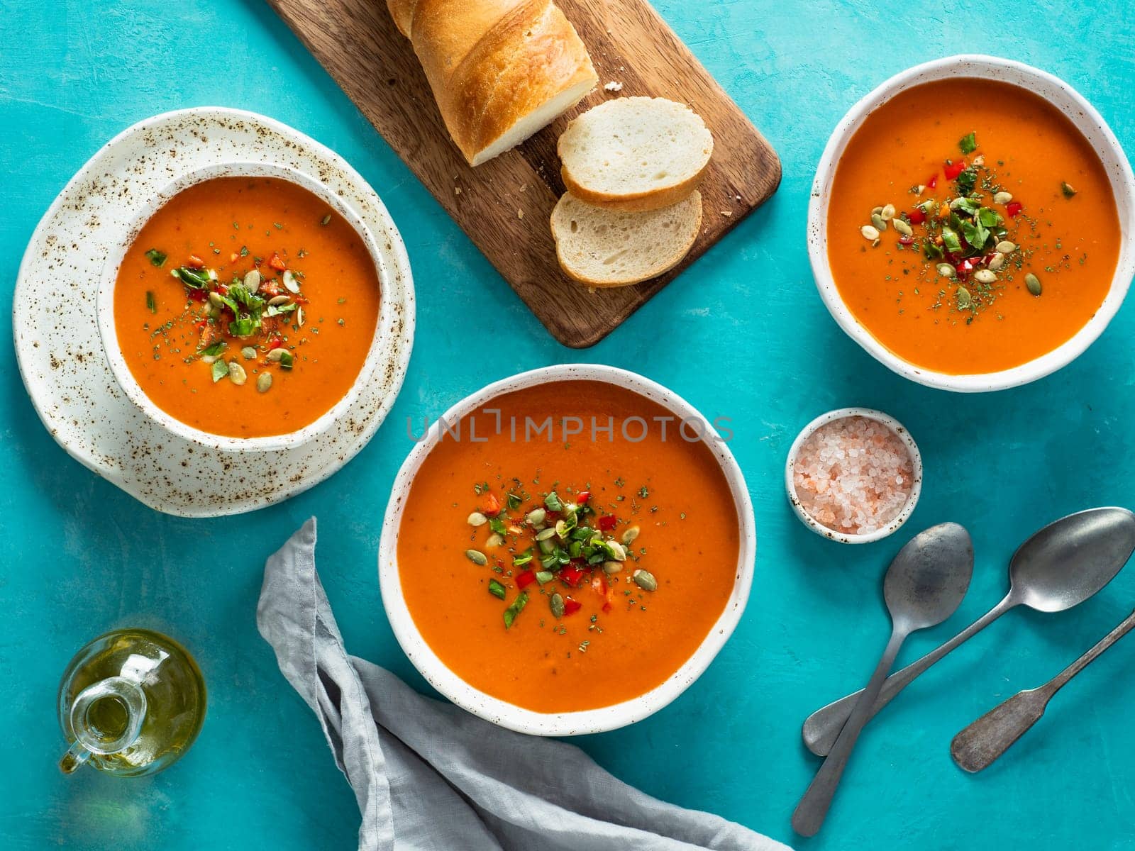 Gaspacho soup on blue tabletop. Three bowls of traditional spanish cold soup puree gaspacho or gazpacho on bright blue background. Top view or flat lay.