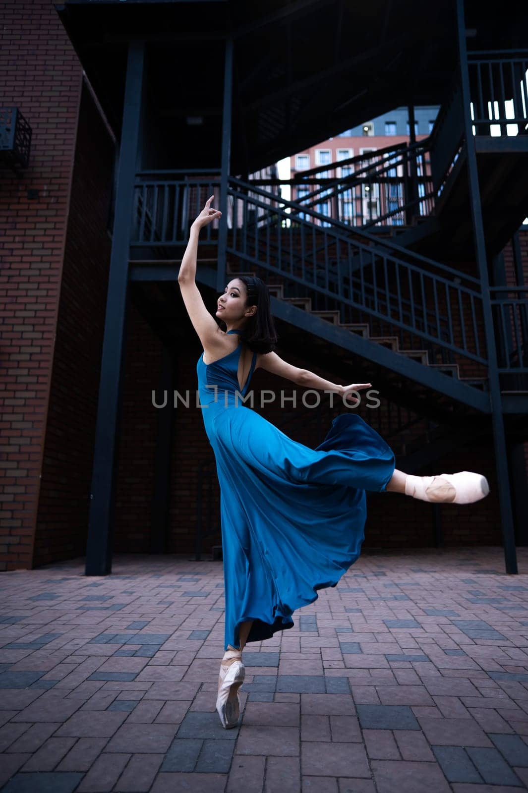 Beautiful Asian ballerina dancing outdoors. Urban landscape