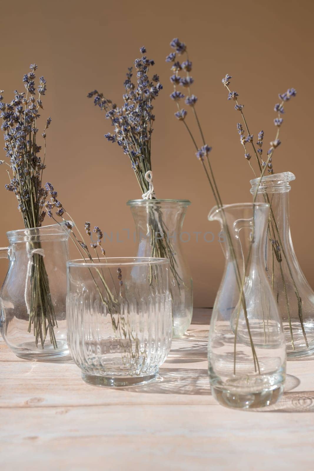 Lavender flowers in glass dishes. Dried herbal flowers on beige background. Minimal still life eco concept. Ideal space for displaying cosmetics with lavender extract. Copy space