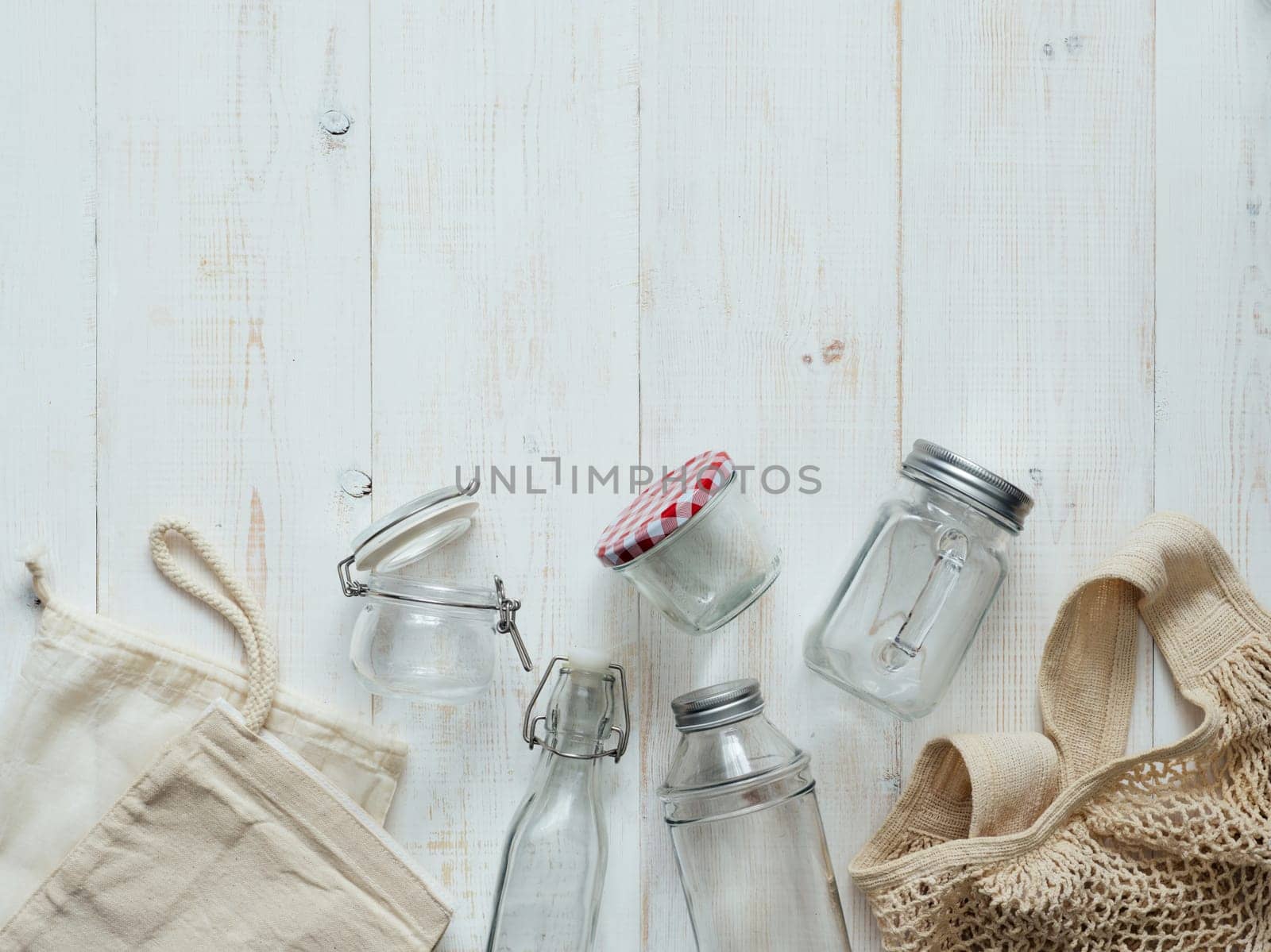 Zero waste concept. Textile eco bags, glass jars and bamboo toothbrush on white wooden background with copy space. Eco friendly and reuse concept. Top view or flat lay