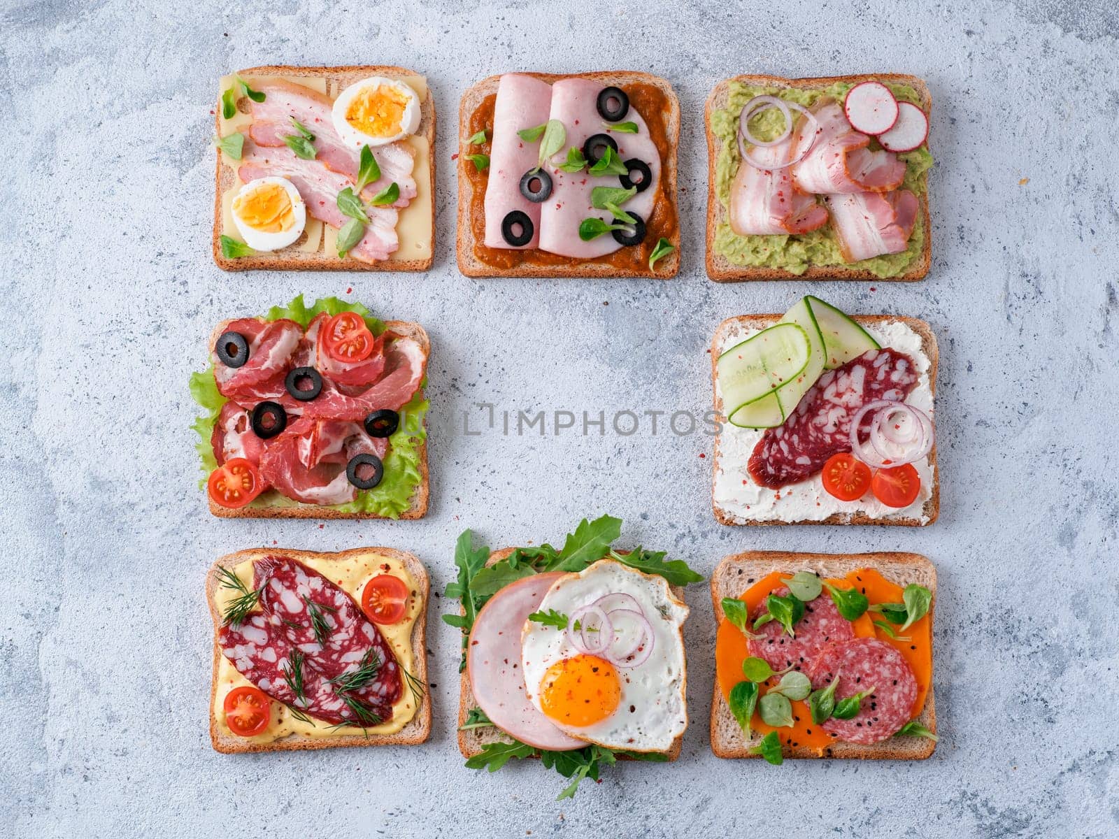 Set of eight different sandwiches with meat in square shape,copy space for text in center.Top view or flat lay.Assortment meat toasts on gray cement background.Idea,creative concept for sausage maker