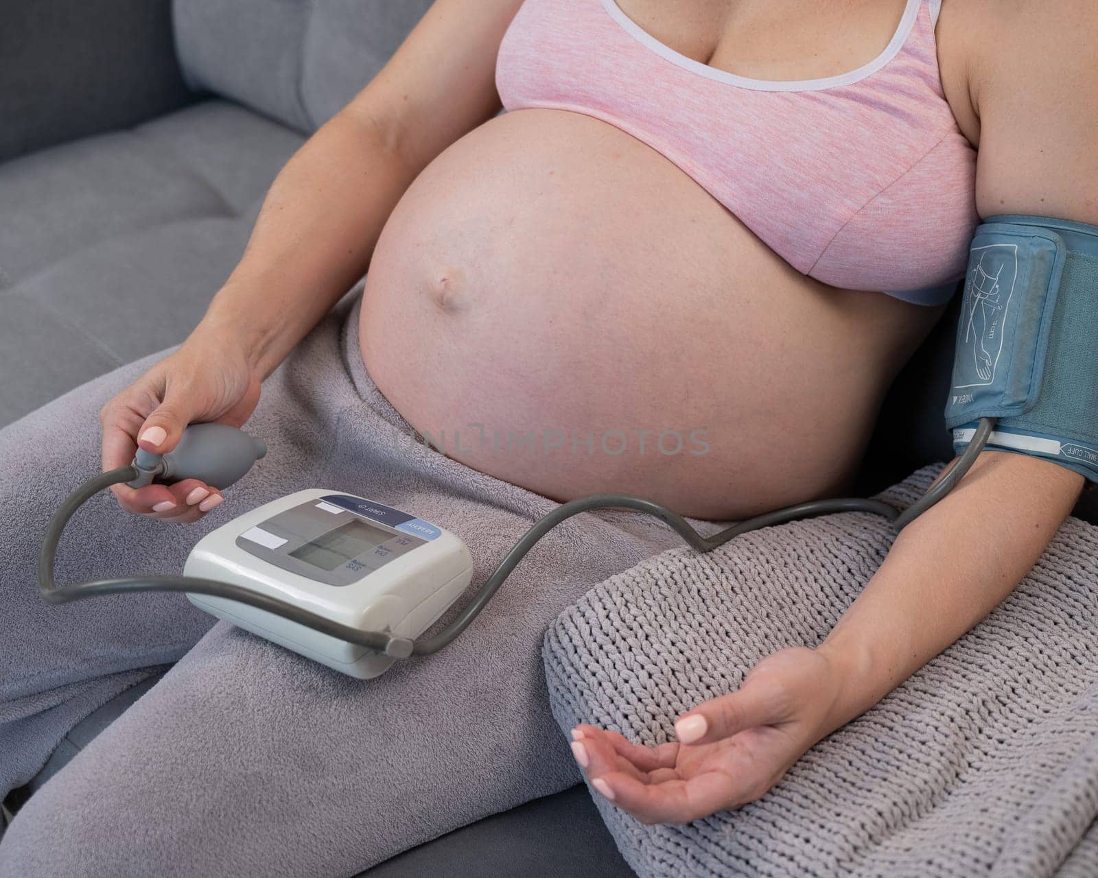 Close-up of the belly of a pregnant woman measuring blood pressure with a tonometer. Hypotension. by mrwed54