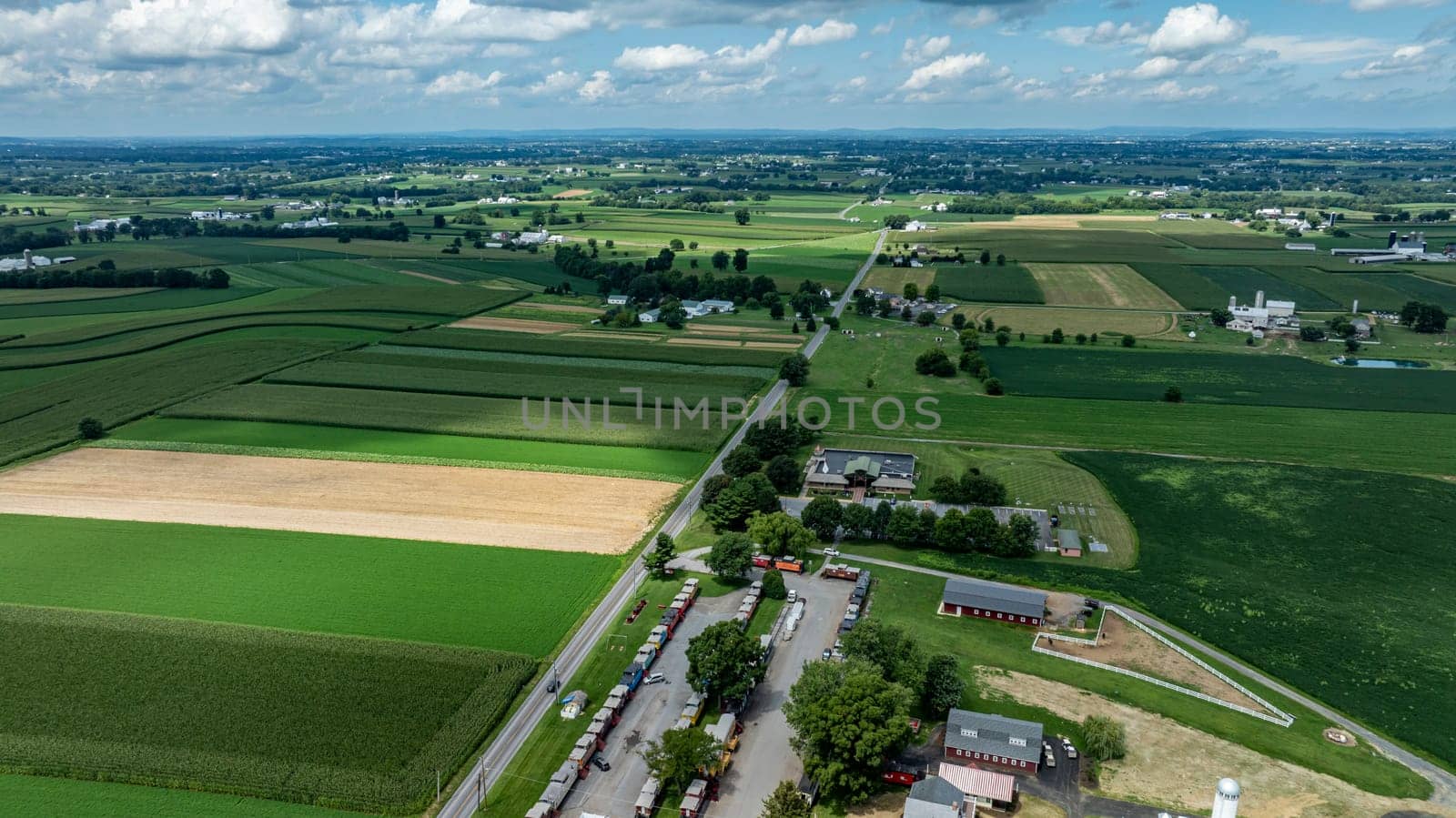 An aerial snapshot captures the lush, ordered fields of the countryside, converging with the quaint charm of a rural homestead.