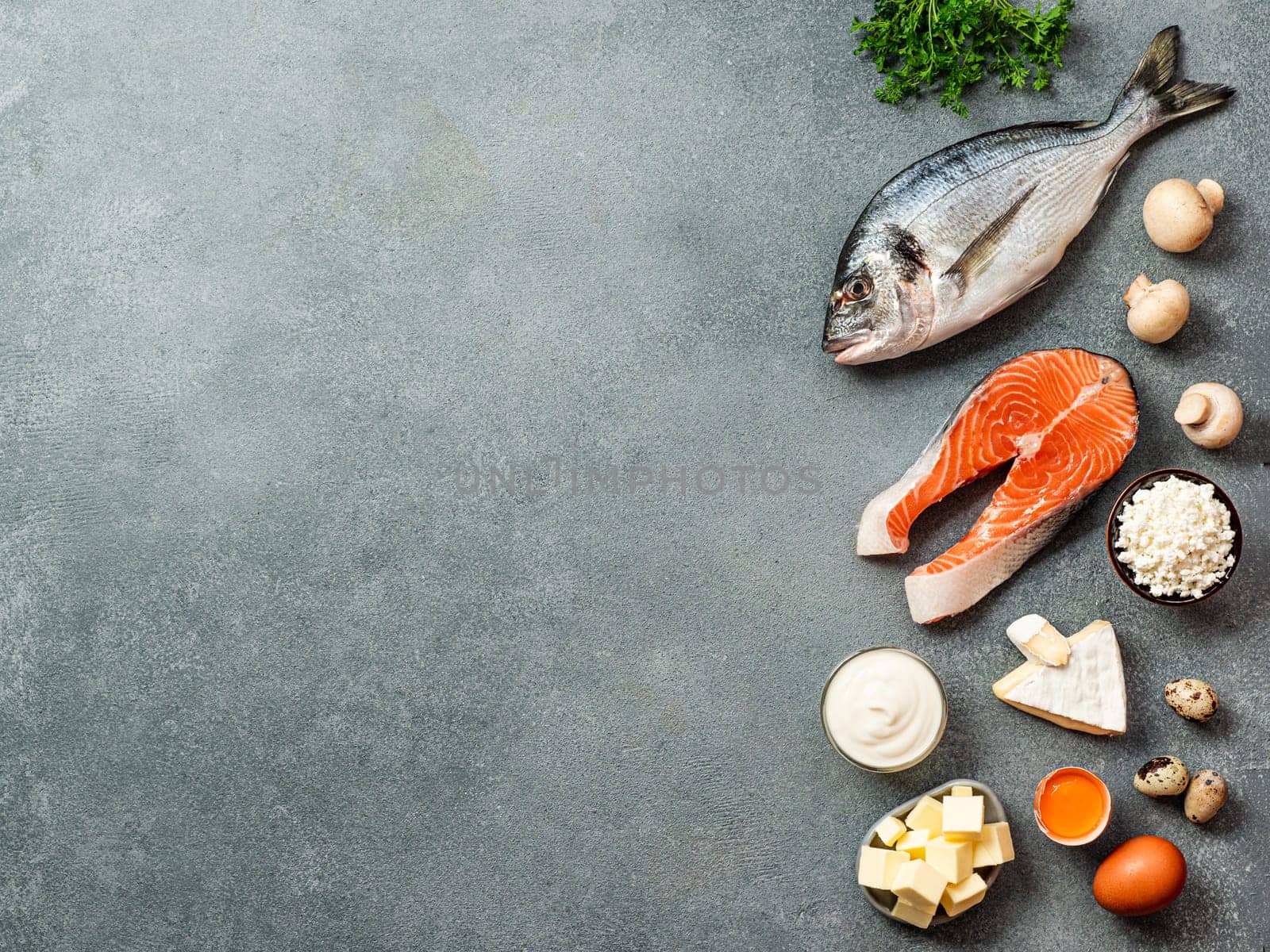 Vaitamin D sources concept with copy space for text. Fish, salmon, dairy products, eggs, mushrooms on gray stone background. Top view or flat lay. Copy space left