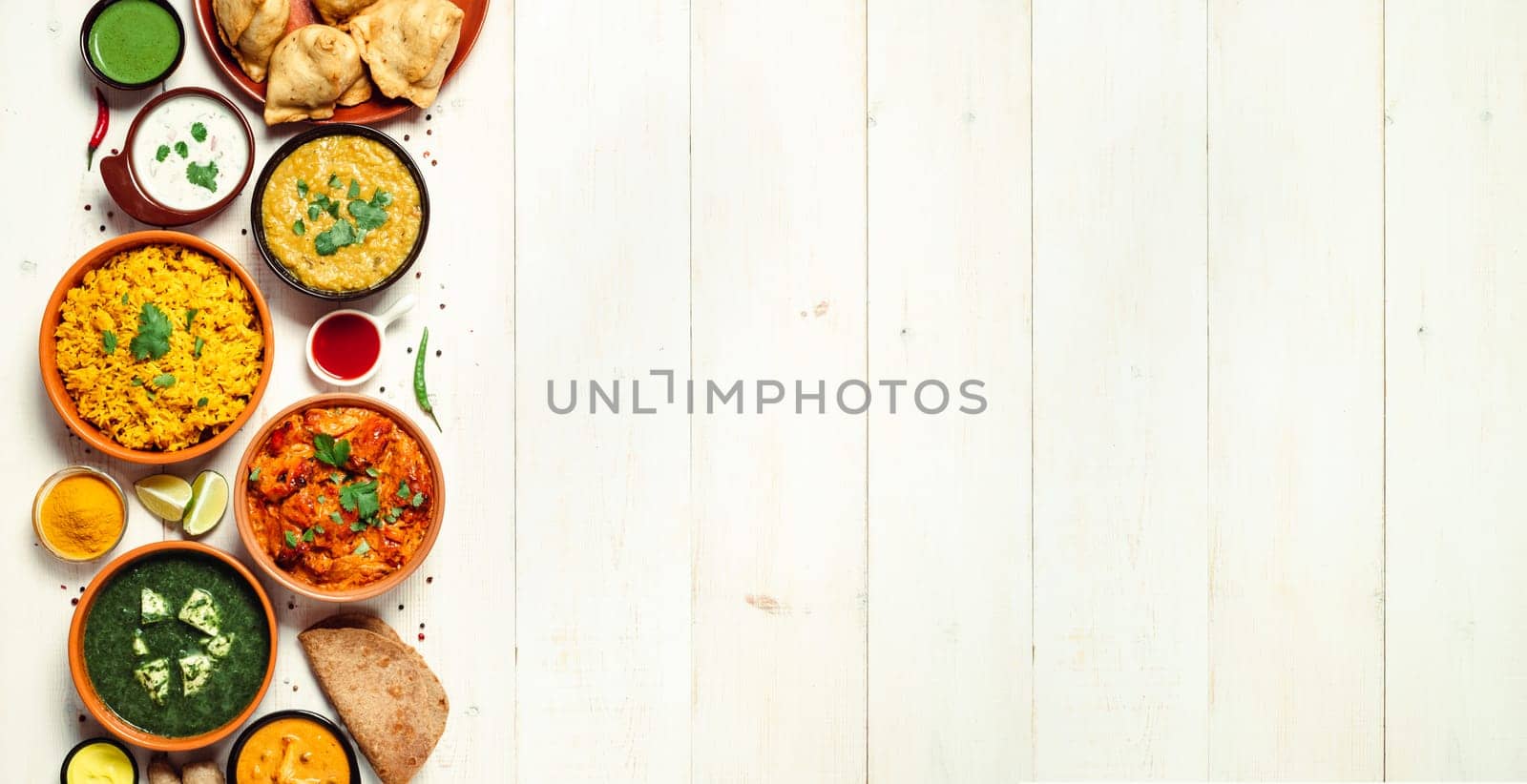 Indian cuisine dishes: tikka masala, dal, paneer, samosa, chapati, chutney, spices. Indian food on white wooden background. Assortment indian meal banner with copy space for text. Top view or flat lay
