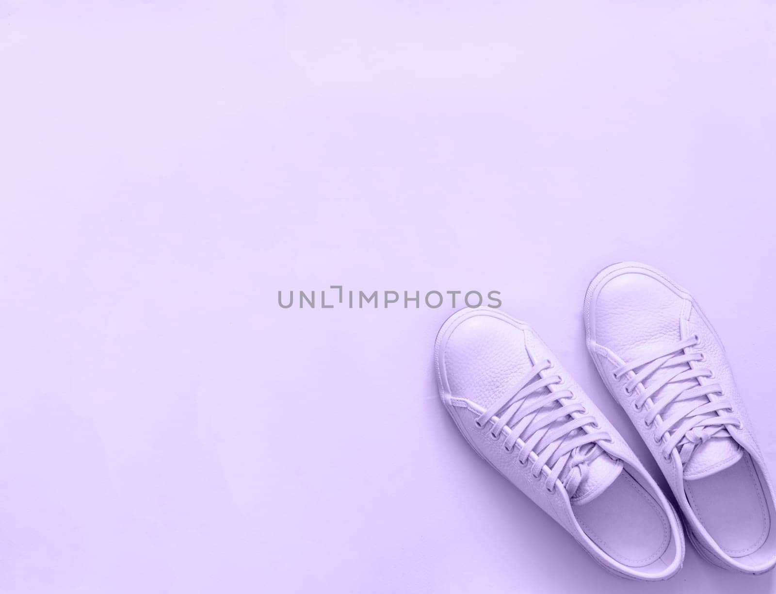 Violet leather sneakers on violet background. Pair of violet sport shoes or sneakers with copy space for text or design. Overhead shot of new violet sneakers,monochrome. Top view or flat lay