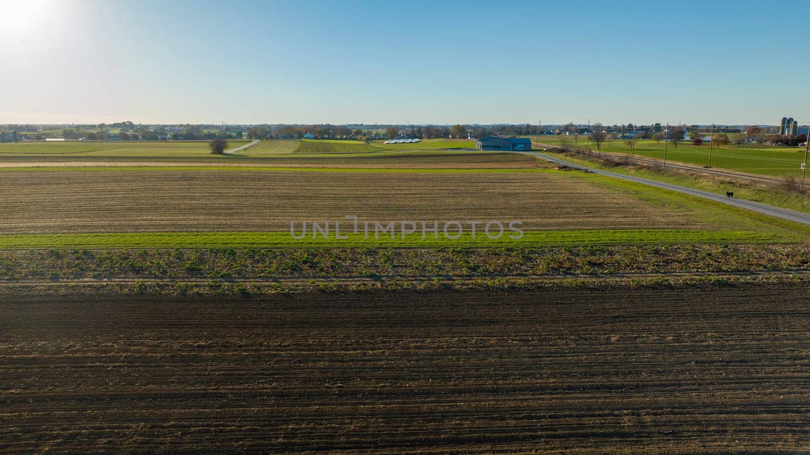 Under clear blue skies, this image spans suburban farmland and its harmonious blend of fields, ideal for real estate and urban planning concepts.
