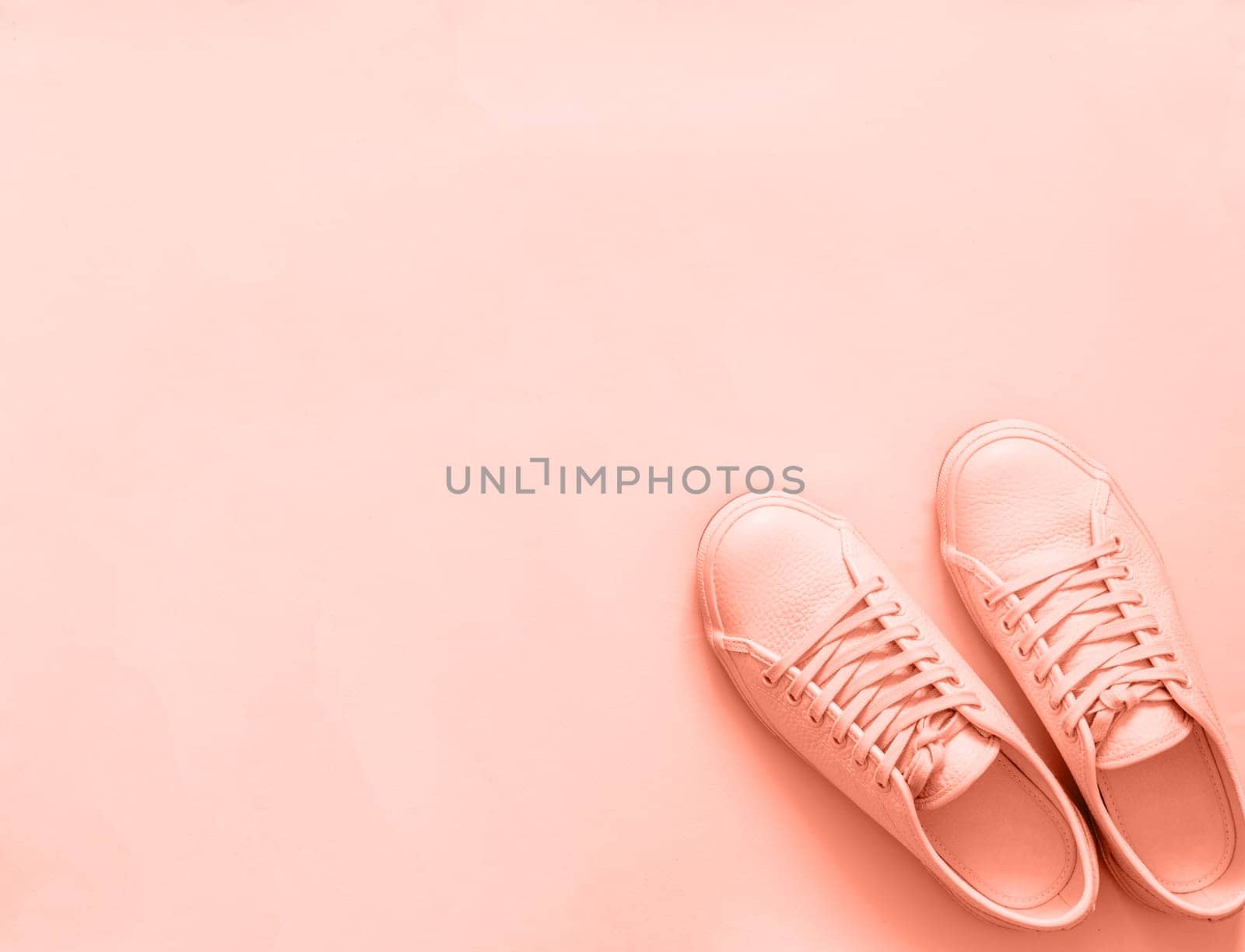 Pink leather sneakers on peach or pink background. Pair of pink sport shoes or sneakers with copy space for text or design. Overhead shot of new pink sneakers,monochrome.Top view or flat lay