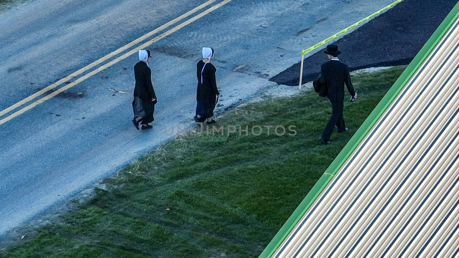 Ronks, Pennsylvania November 14, 2023 - The fading light of twilight accompanies three Amish individuals on their quiet trek along a country lane, a moment of peace and routine.