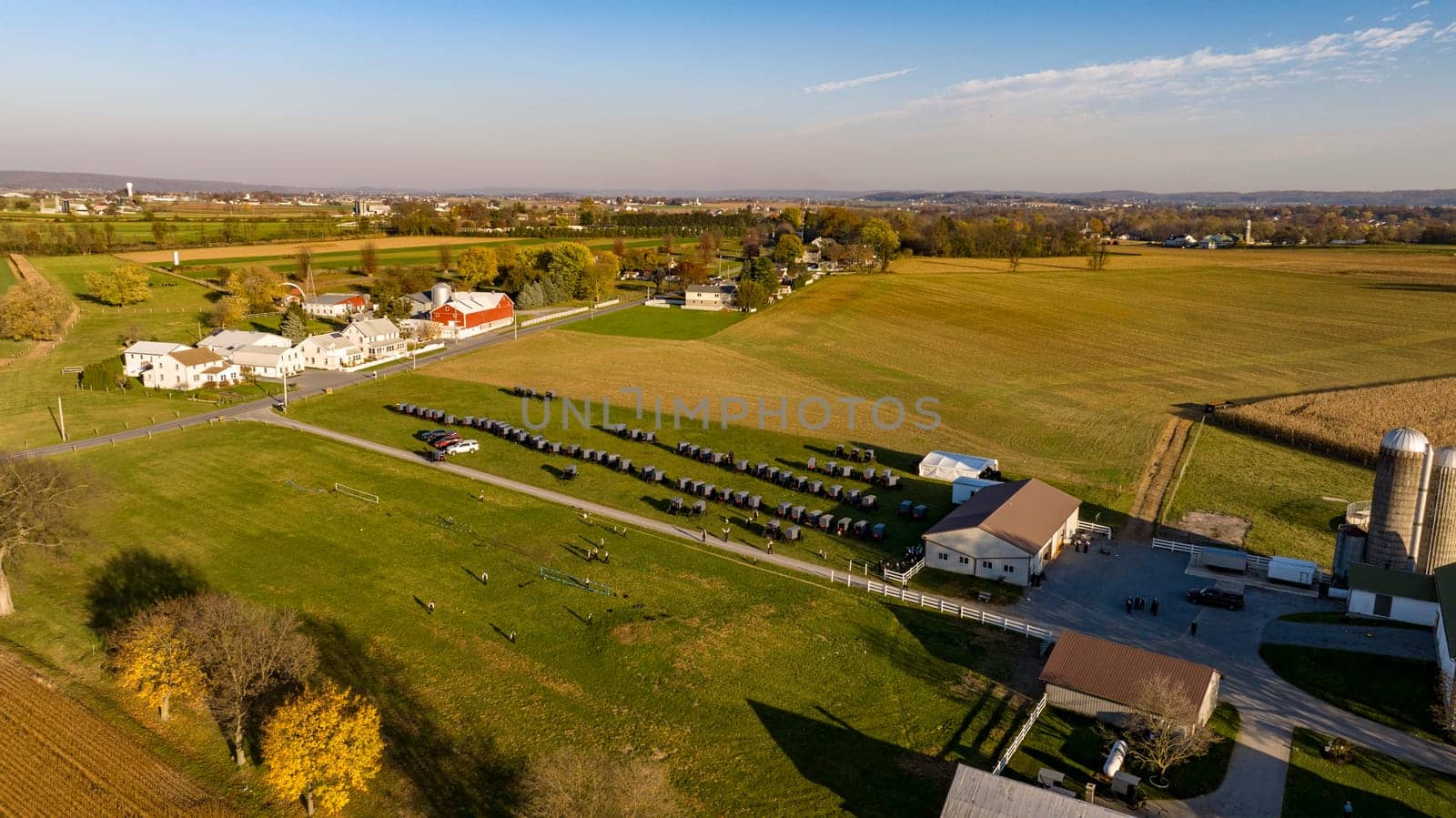 This aerial image displays the vast beauty of Amish farmland at dusk, with a serene sunset backdrop, highlighting the community's harmonious blend with nature. for an Amish wedding