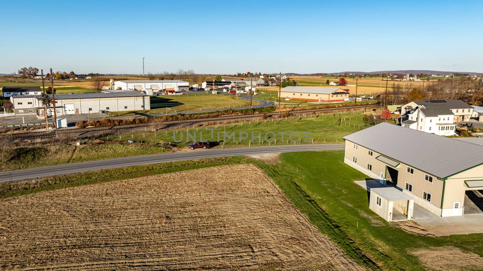 This image beautifully contrasts industrial buildings with a surrounding autumnal rural landscape, perfect for illustrating rural industrial development.