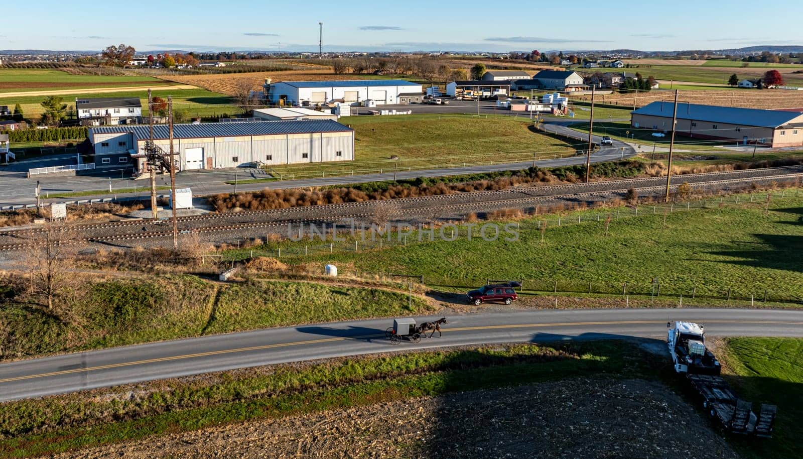 Captured in Lancaster, PA, this image contrasts a traditional Amish buggy against a backdrop of modern industrial buildings, showcasing the blend of old and new.