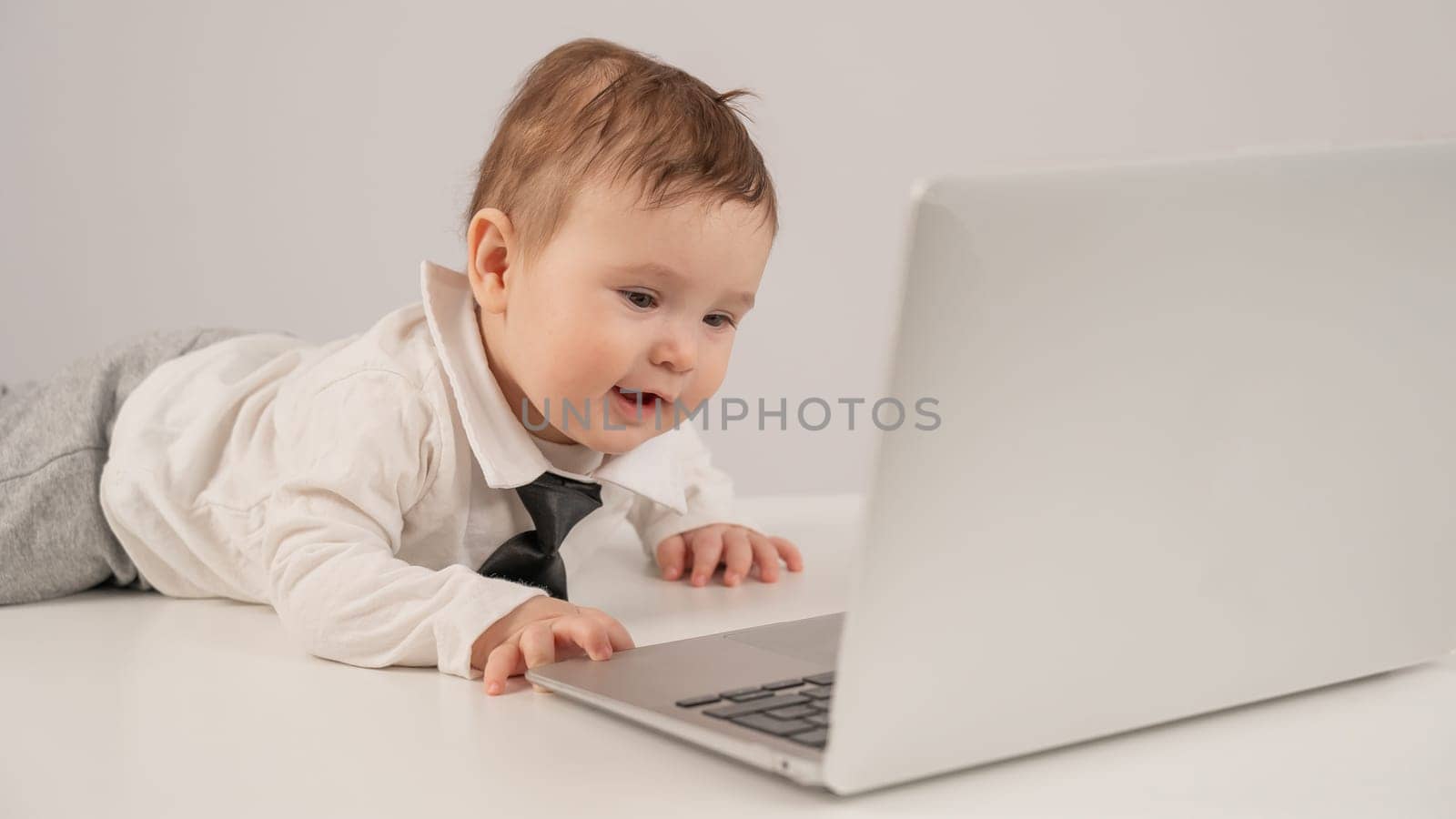 Cute baby boy in a tie working at a laptop. by mrwed54