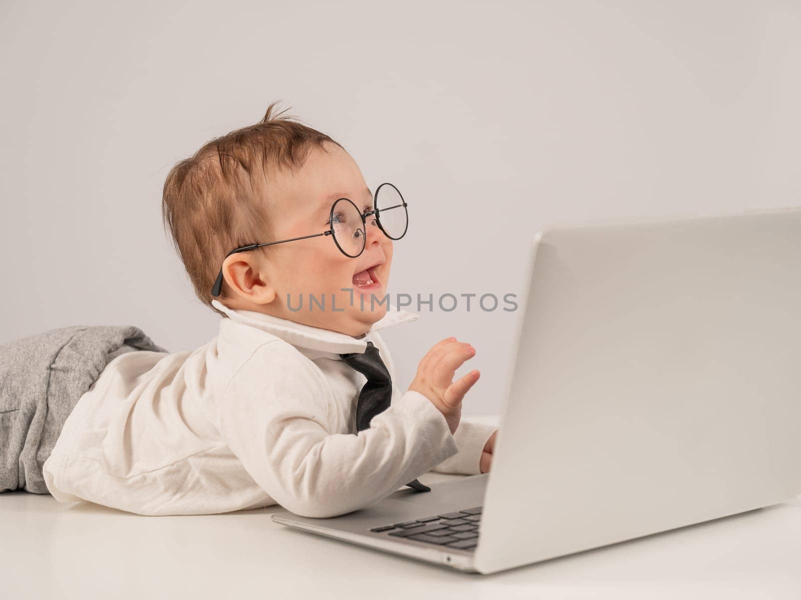 Cute baby in glasses and suit working on laptop. by mrwed54