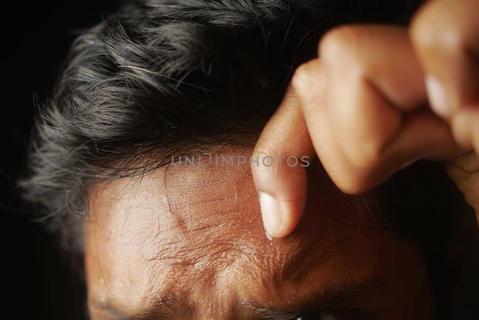 closeup of sweat on forehead against dark background