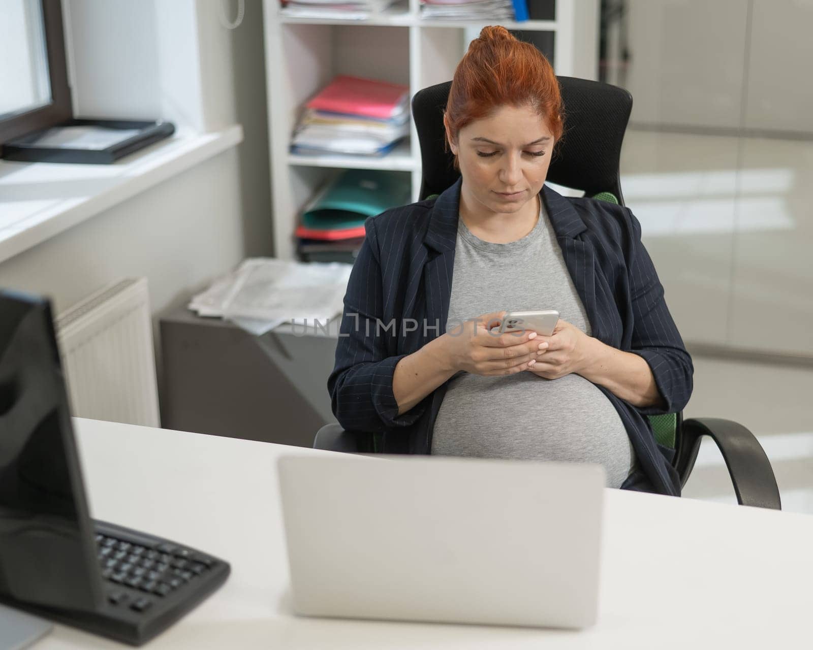 Pregnant woman using mobile phone in office