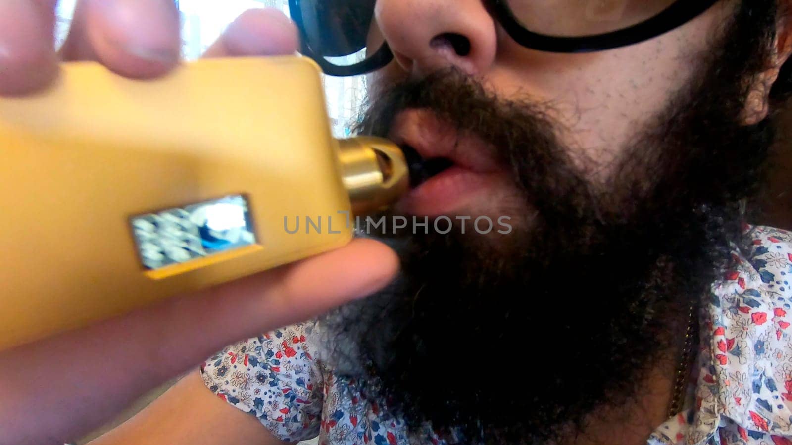 Close-up of a bearded man inhaling from a handheld vaping device