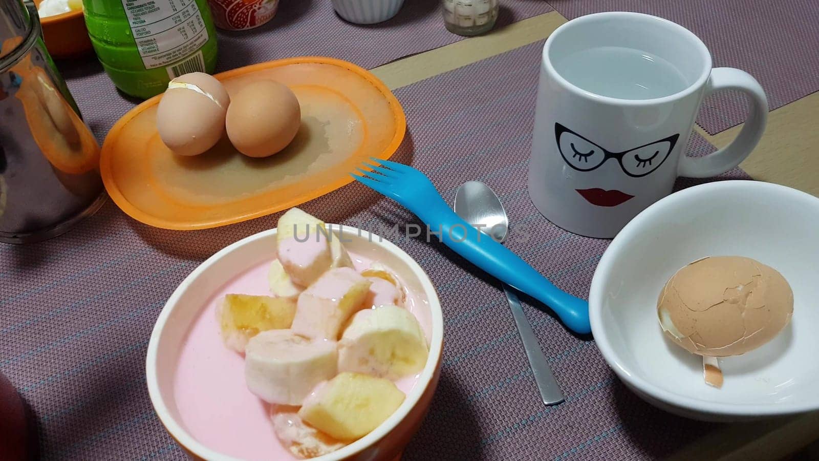 Simple home breakfast scene with boiled eggs, sliced bananas in a bowl, and a playful mug